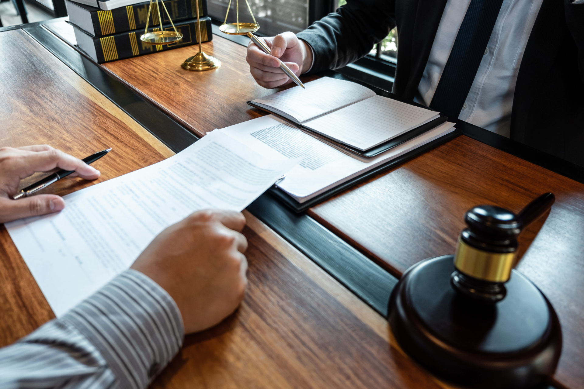 Two men are sitting at a wooden table signing a document.