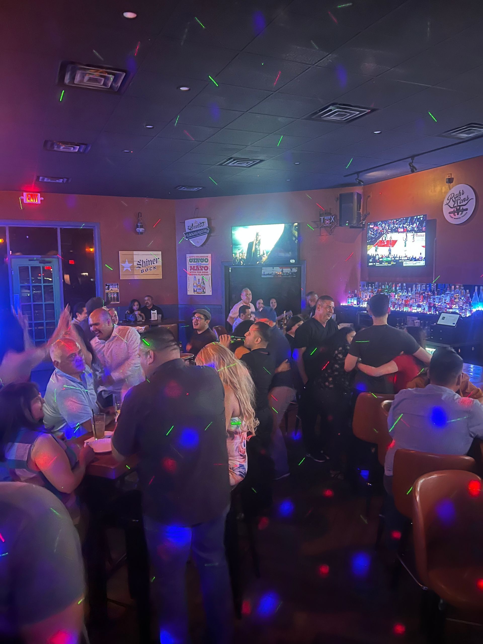 A large group of people are dancing in a bar.