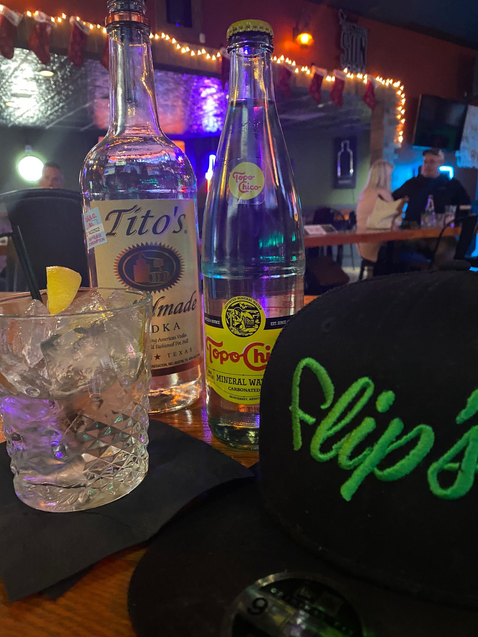 A bottle of tito 's tequila next to a glass of water