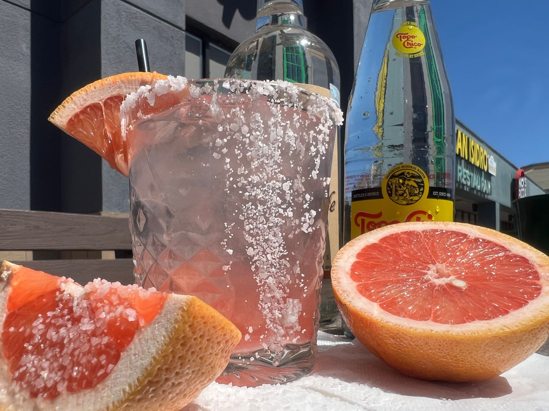 A glass of grapefruit juice next to a bottle of tequila
