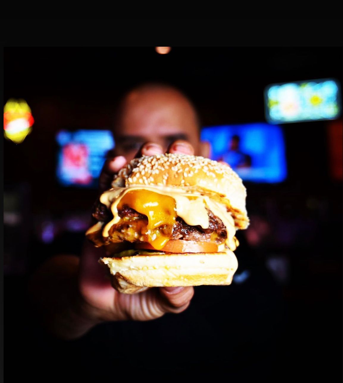 A man is holding a cheeseburger in his hand
