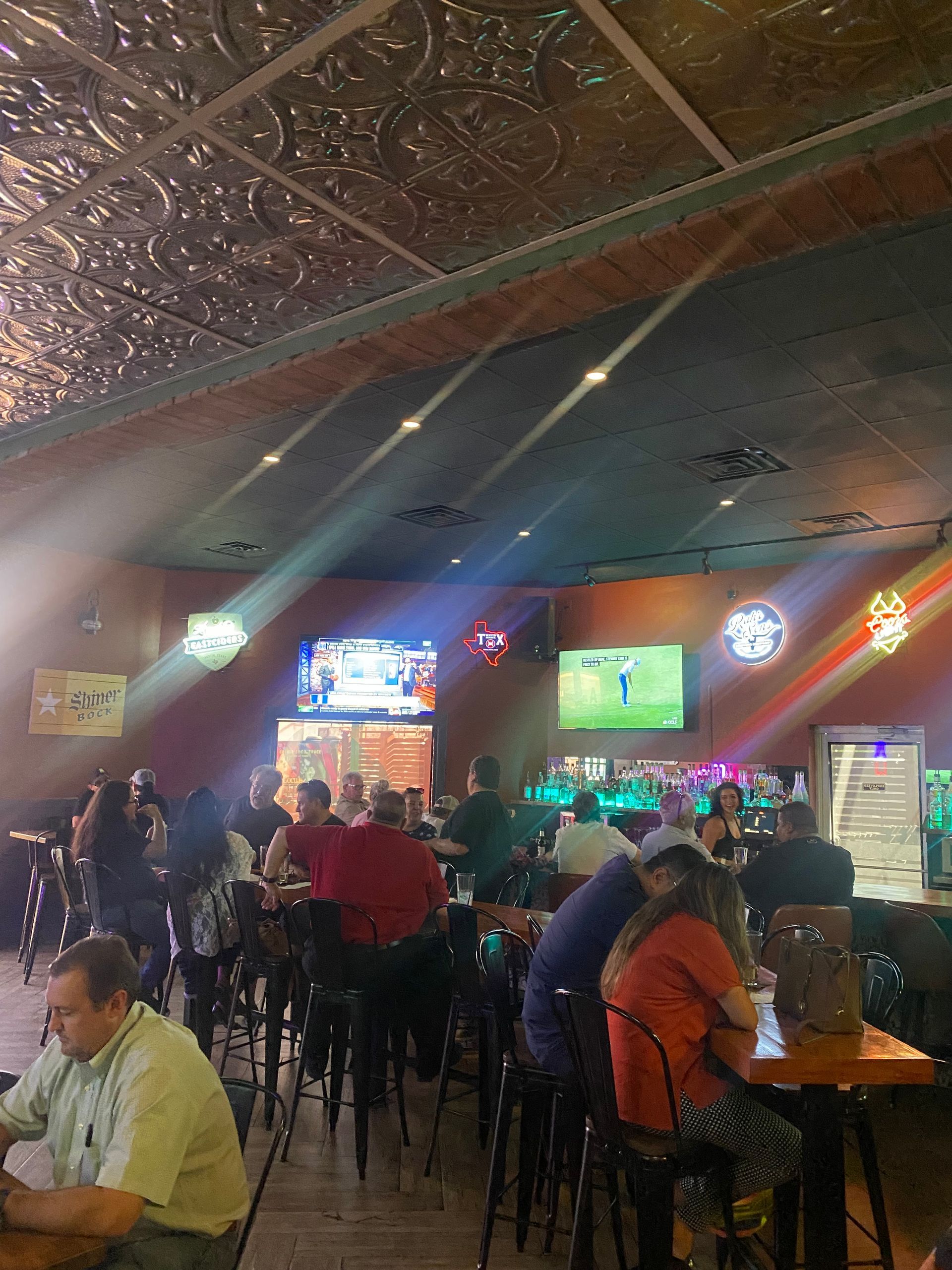 A group of people are sitting at tables in a bar.