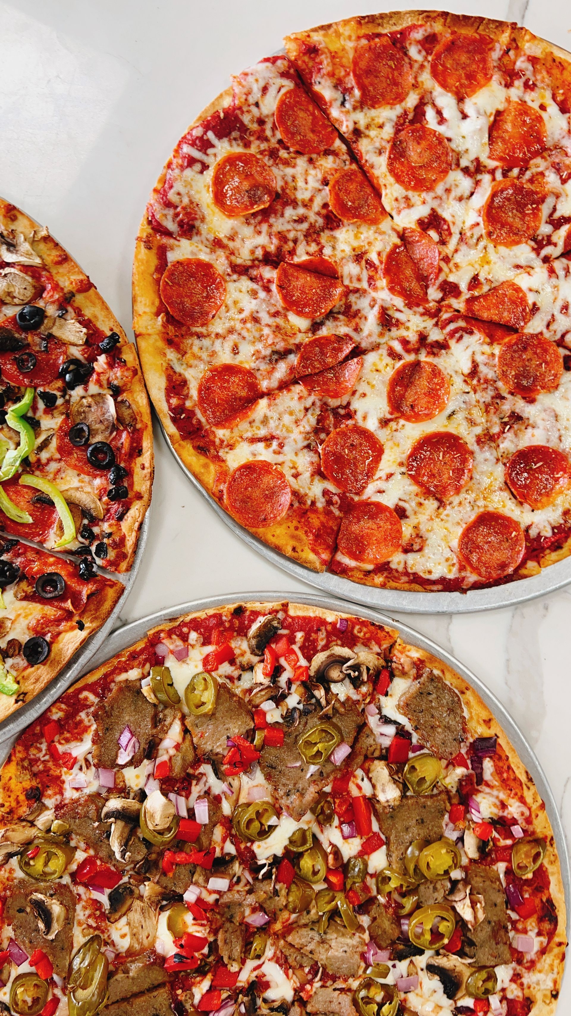 Three different types of pizzas are sitting on a table.
