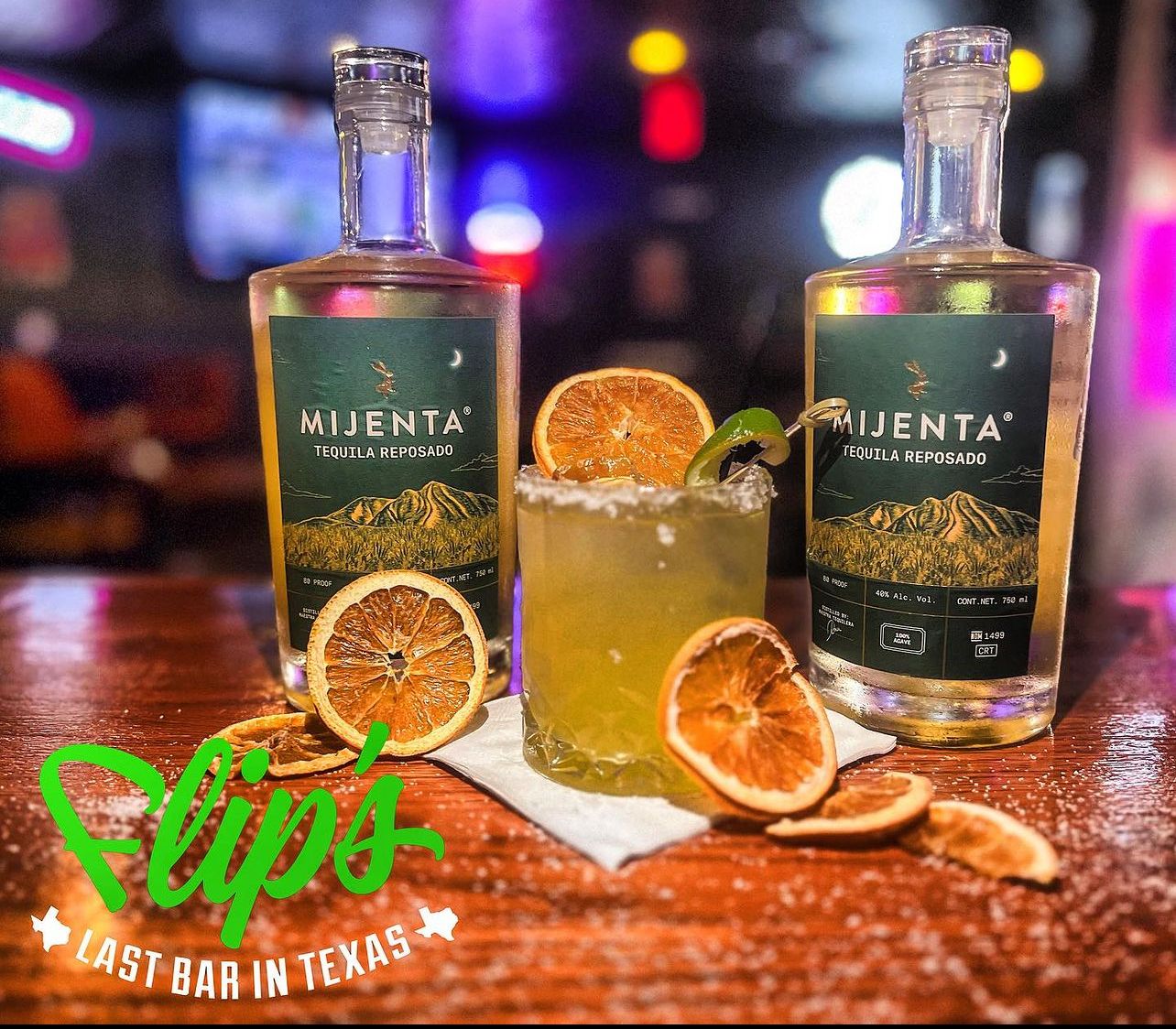 Two bottles of nijenta next to a drink on a table