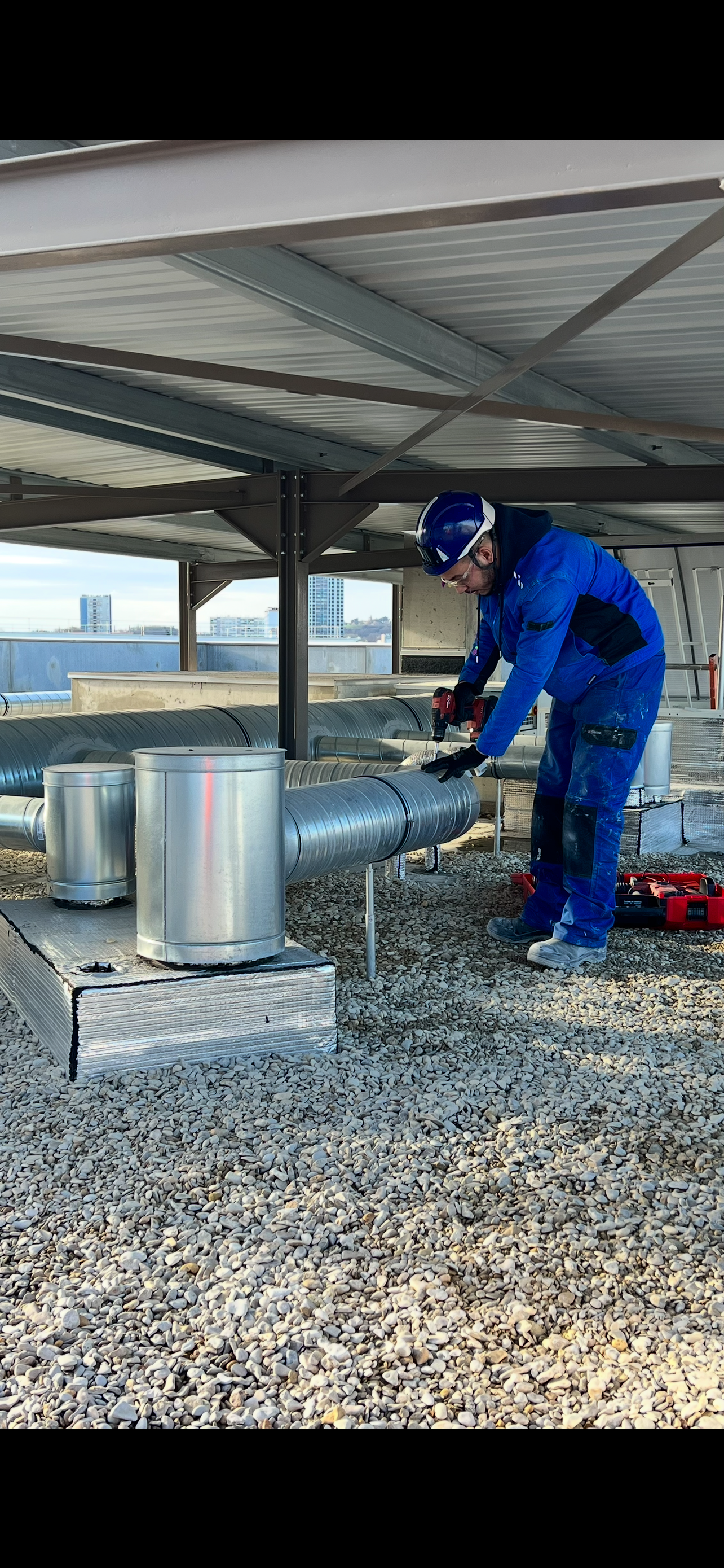 Toit avec plusieurs grandes unités CVC, blanches et grises, sous un ciel ensoleillé.