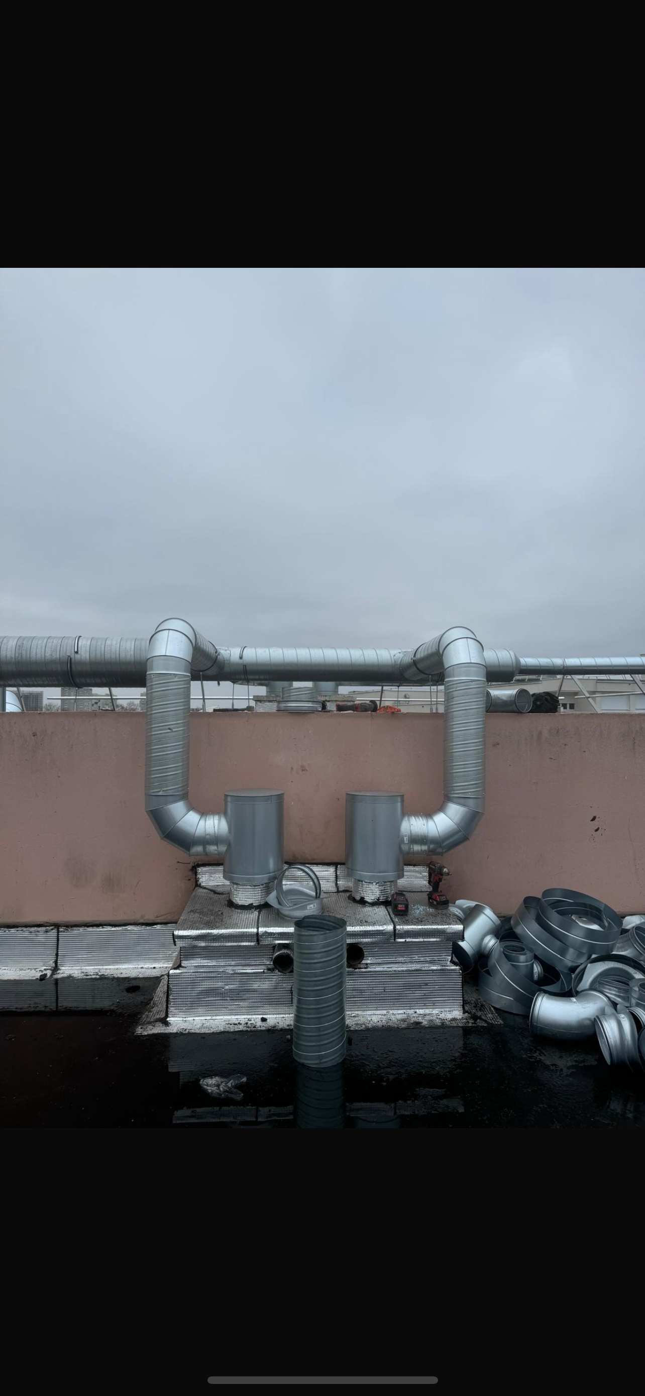 Des tuyaux sur un toit, en forme de U, sous un ciel gris.