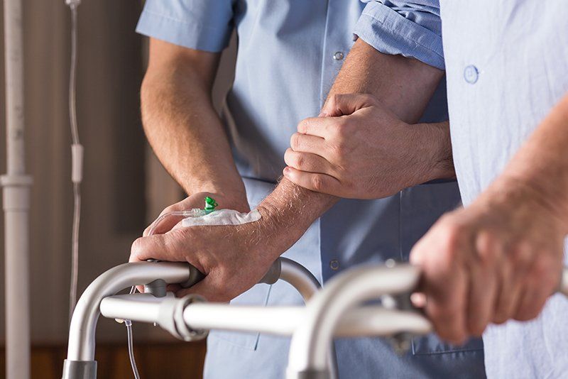 infermiere aiuta paziente con flebo al deambulatore