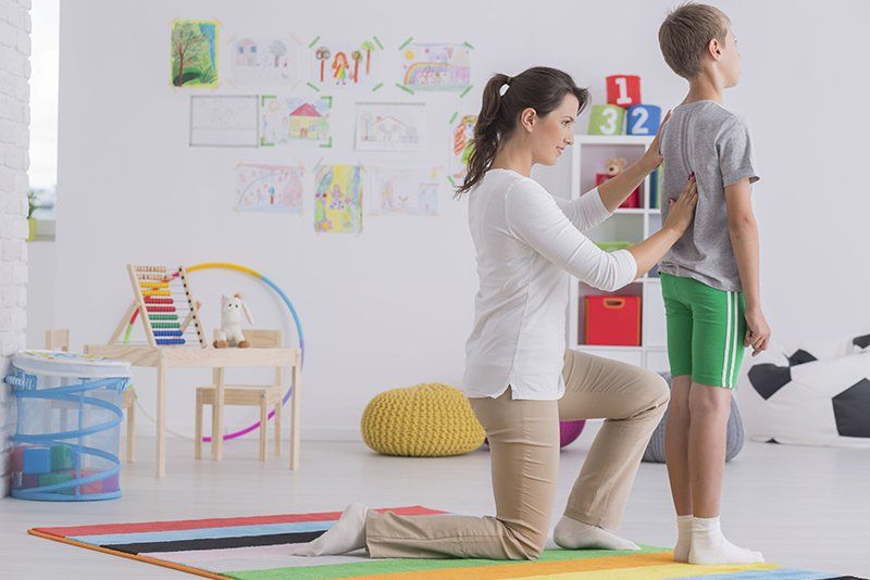 fisioterapista palpa la colonna vertebrale di un bambino in sala riabilitazione