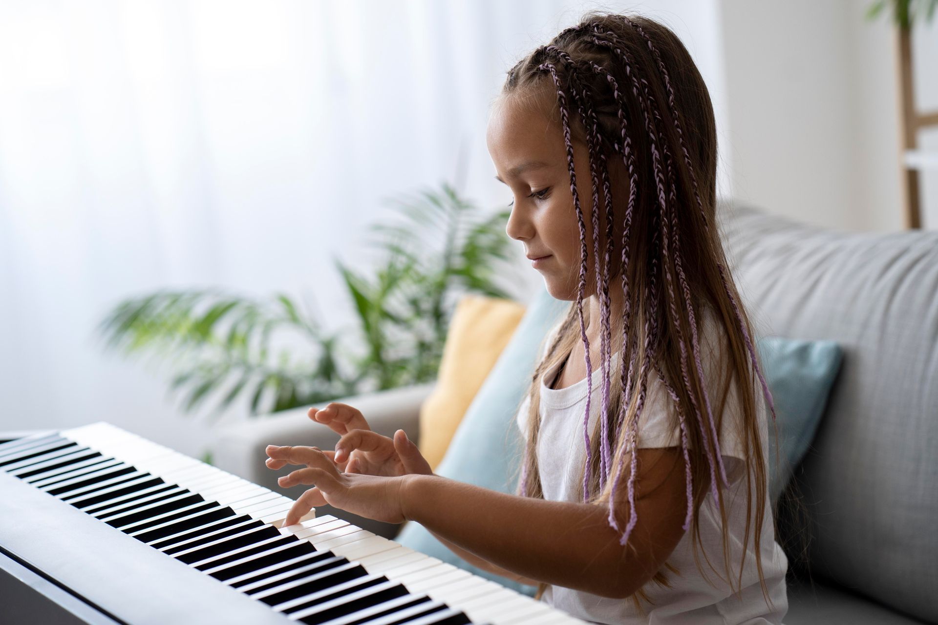 A little girl is sitting on a couch playing a piano.