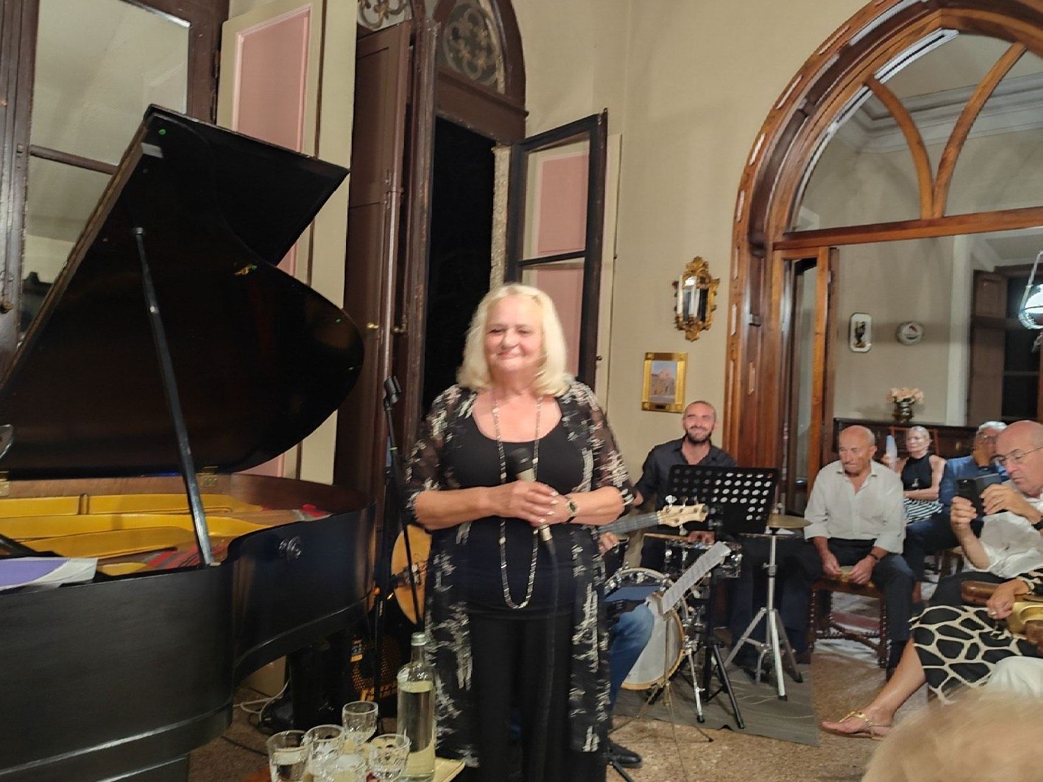 A woman is standing in front of a piano in a room.