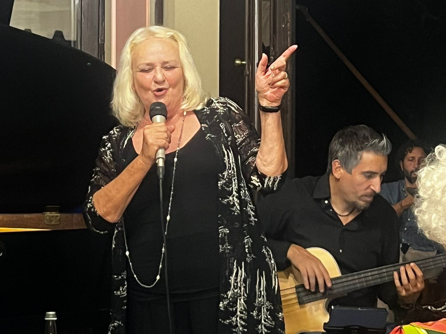 A woman singing into a microphone next to a man playing a guitar