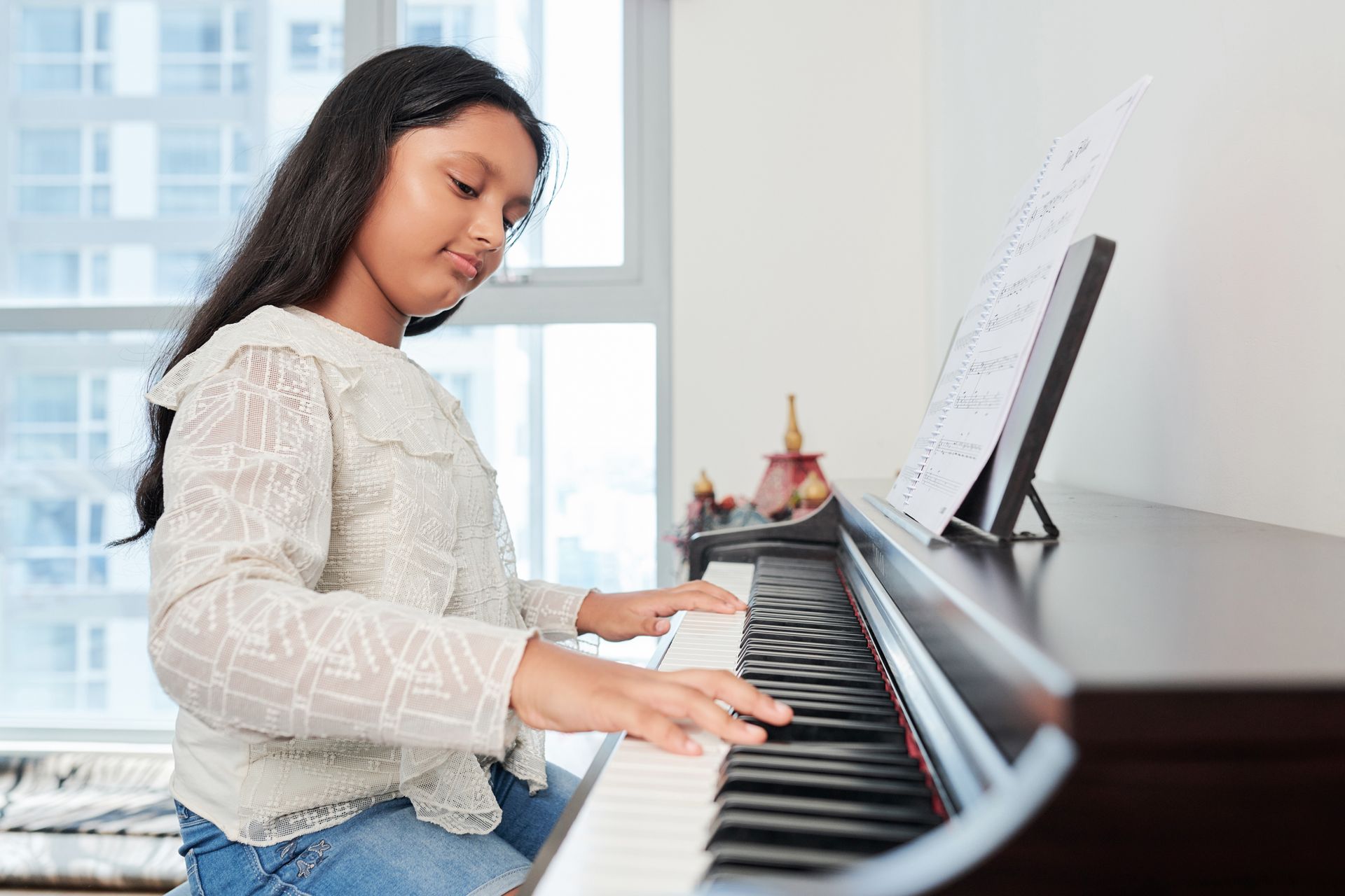 A young girl is playing a piano in a living room.