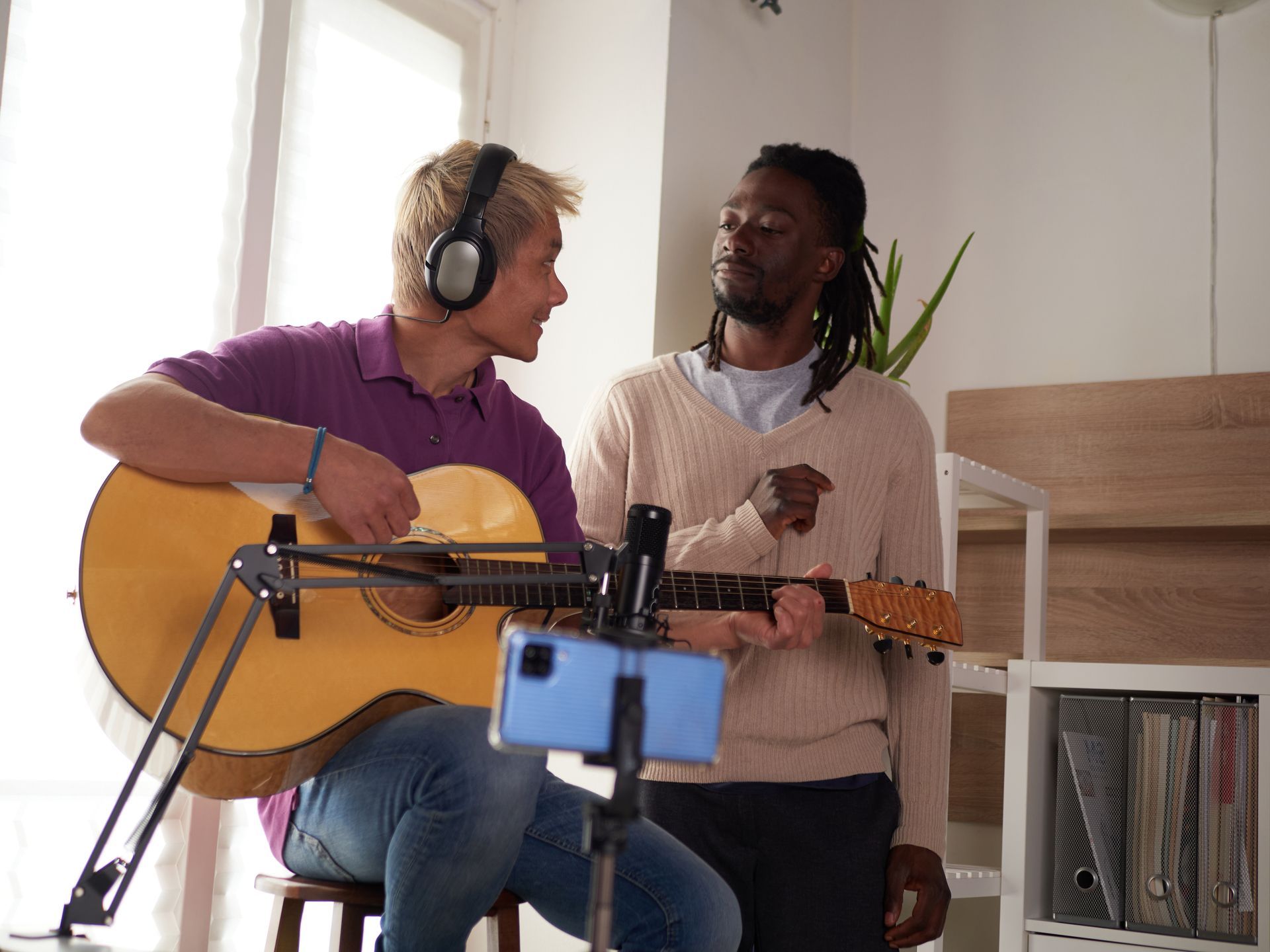 Two men are playing guitars and singing into a microphone.