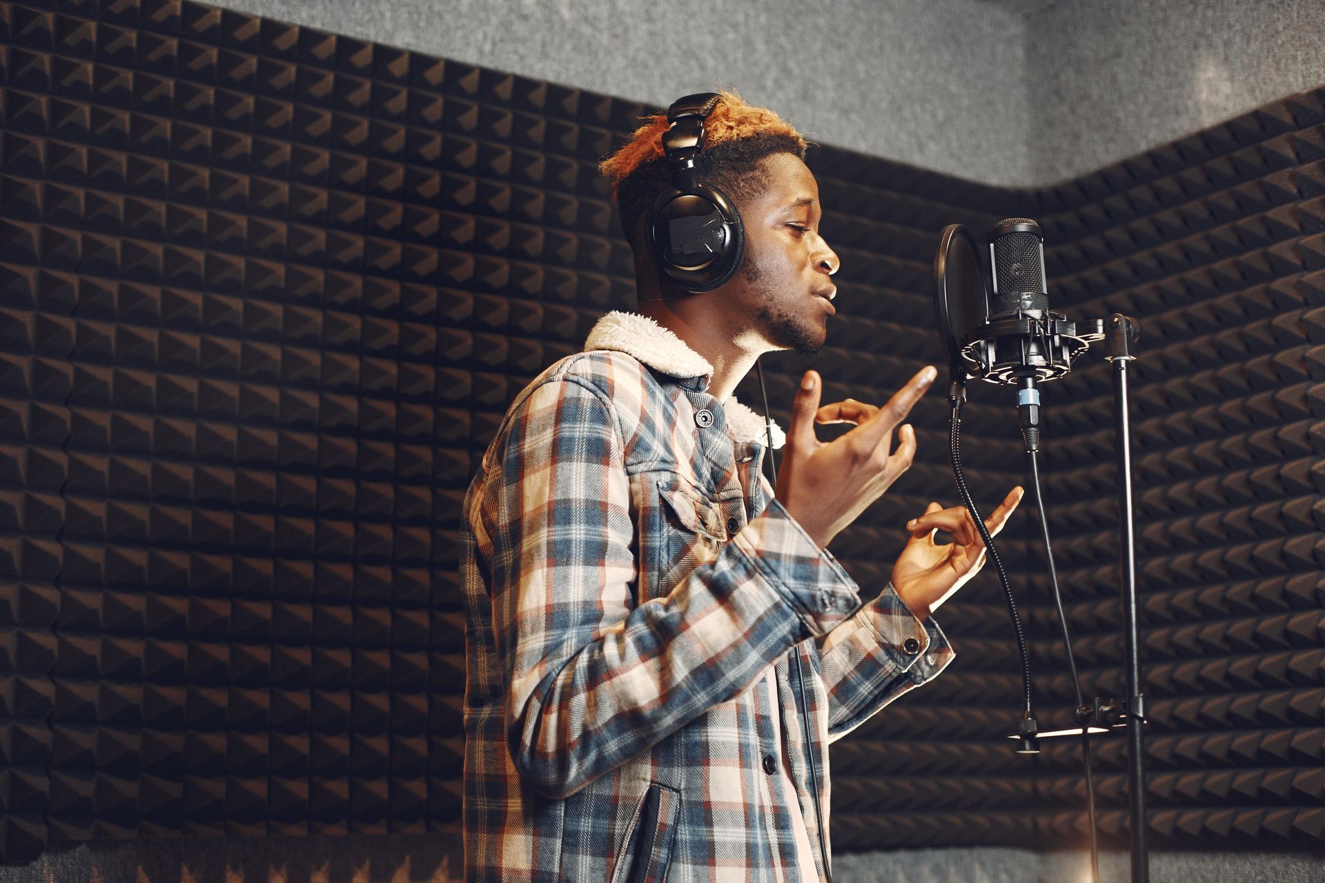 A man is singing into a microphone in a recording studio.