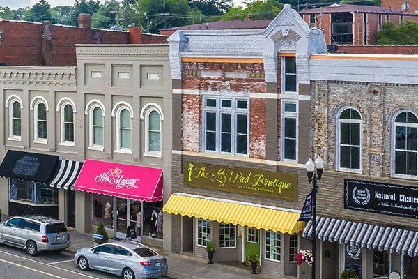 A row of stores on a city street with cars parked in front of them