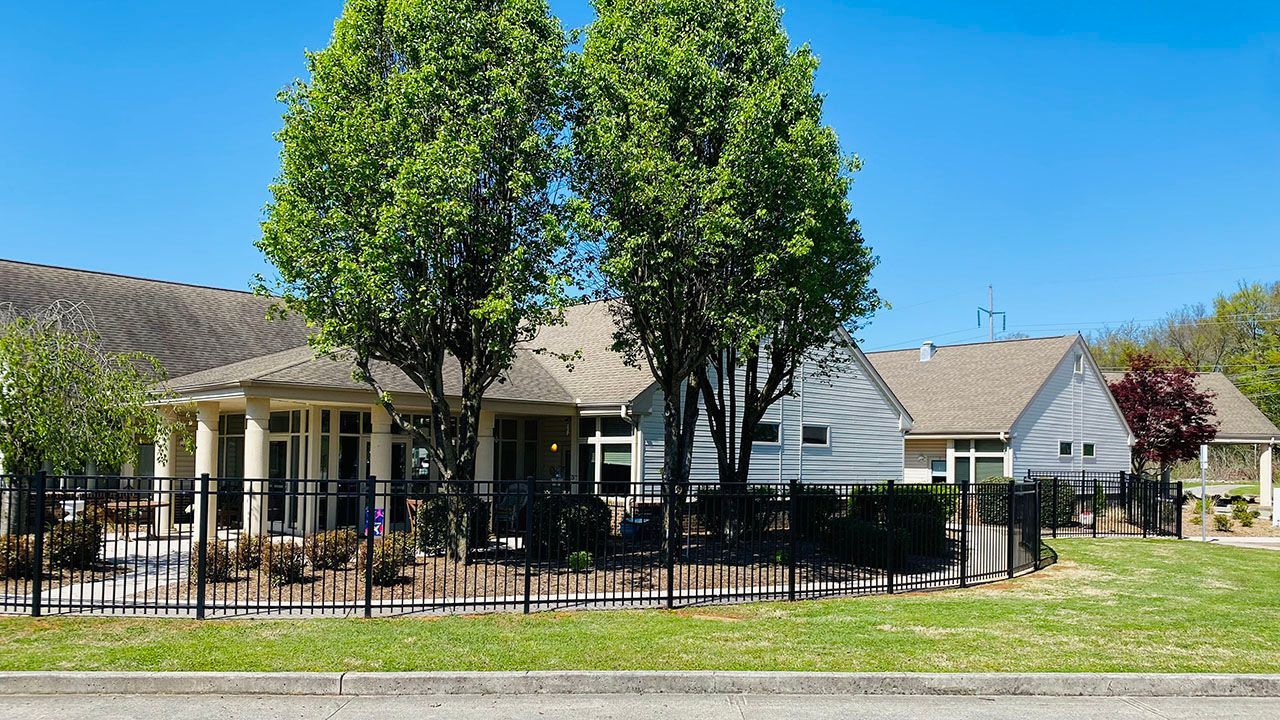 A house with a fence and trees in front of it.