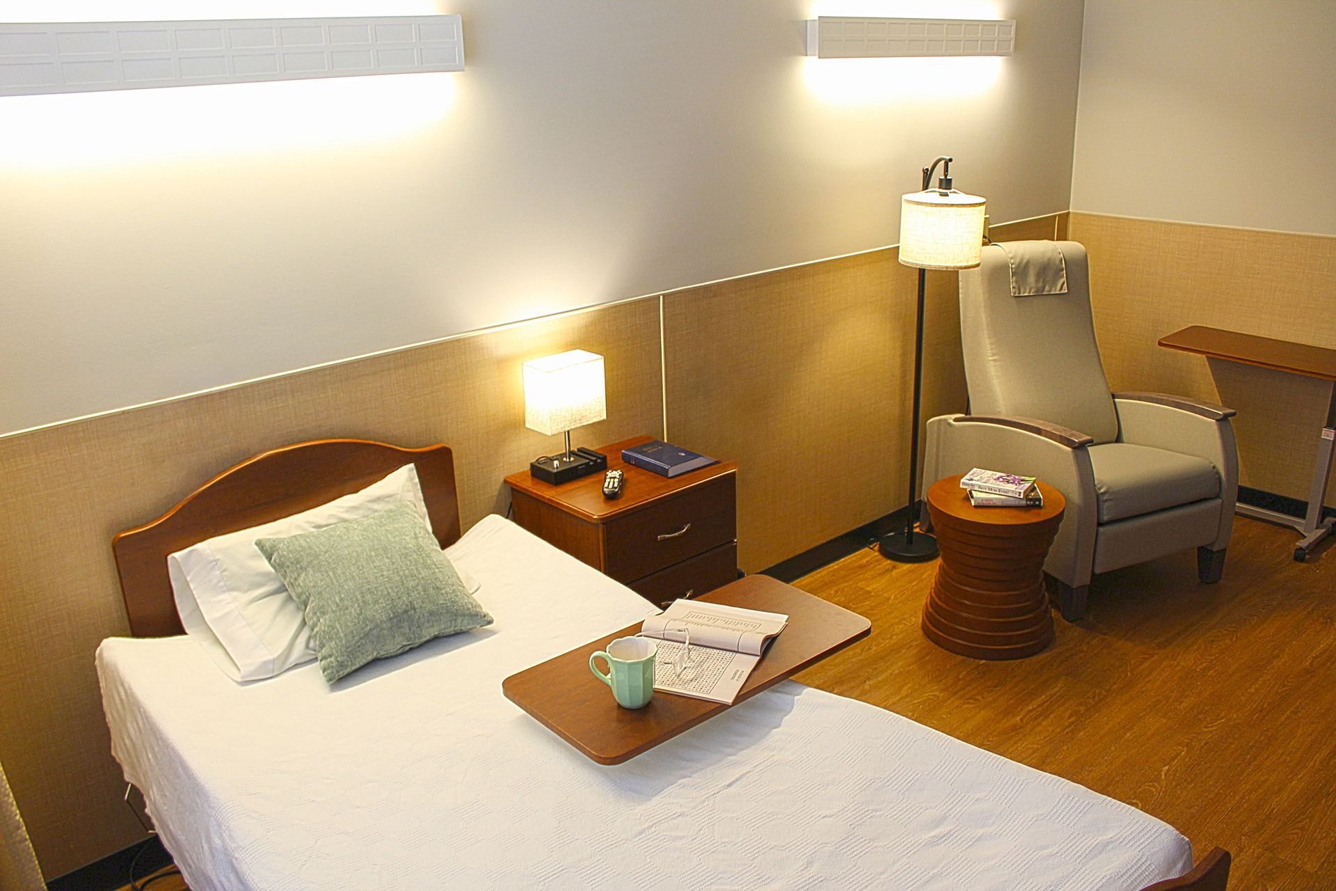 A bedroom with a bed a chair a table and a lamp