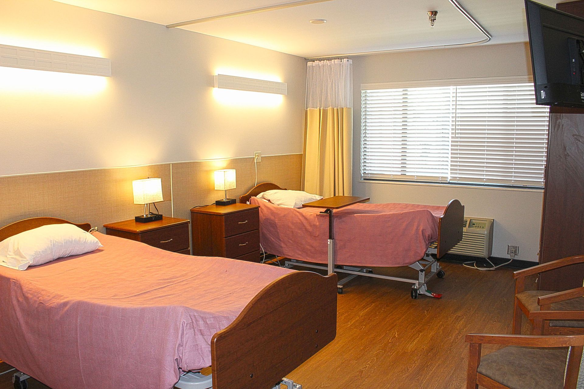 A hospital room with two beds and a television