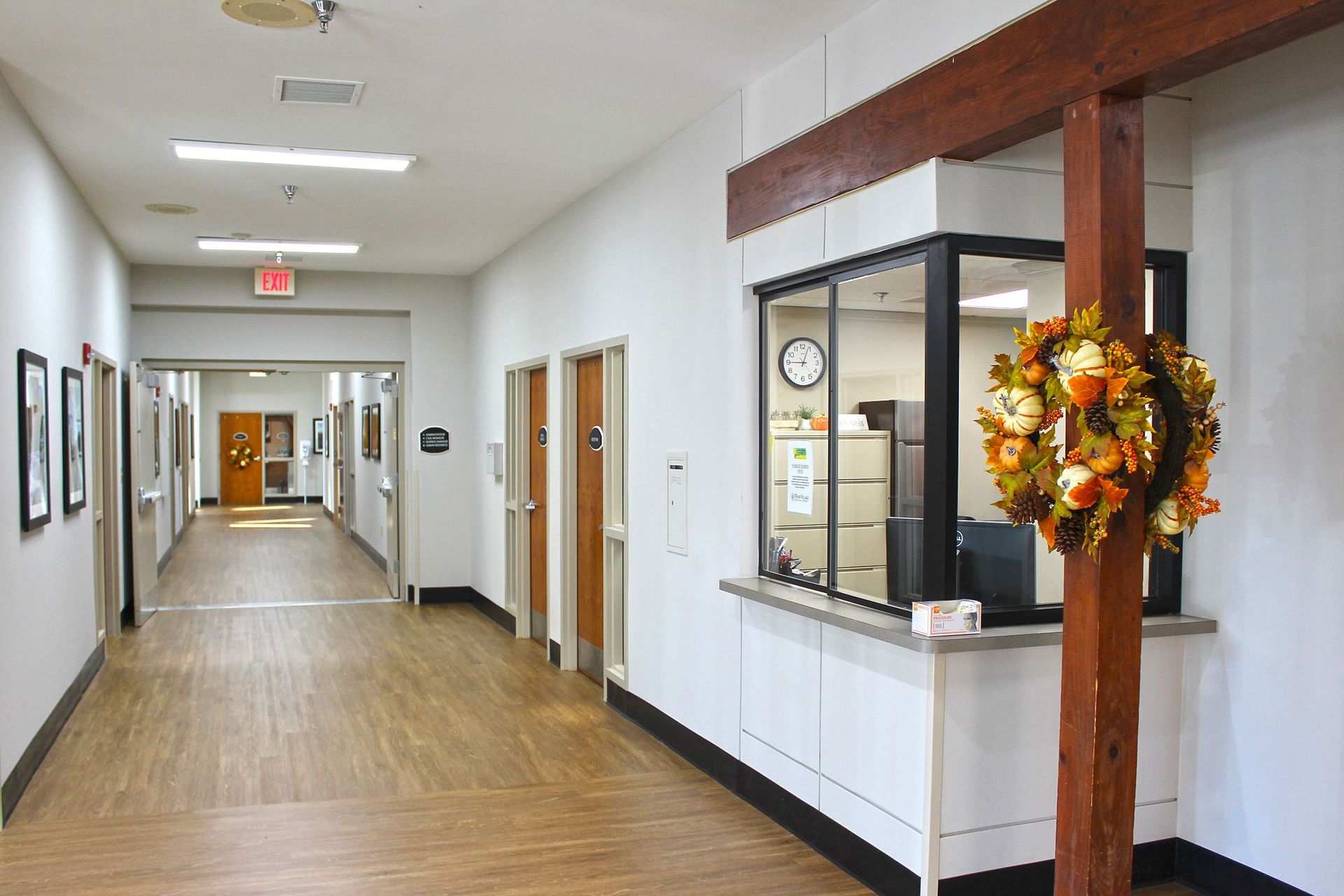 A long hallway with a clock on the wall and a wreath on the wall.