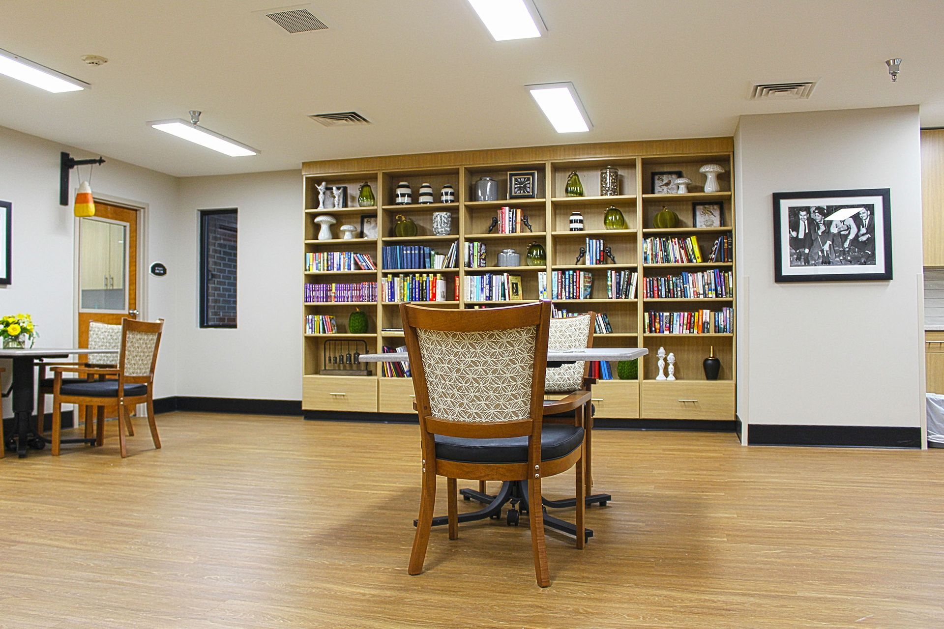 A large room with a table and chairs in front of a bookshelf.