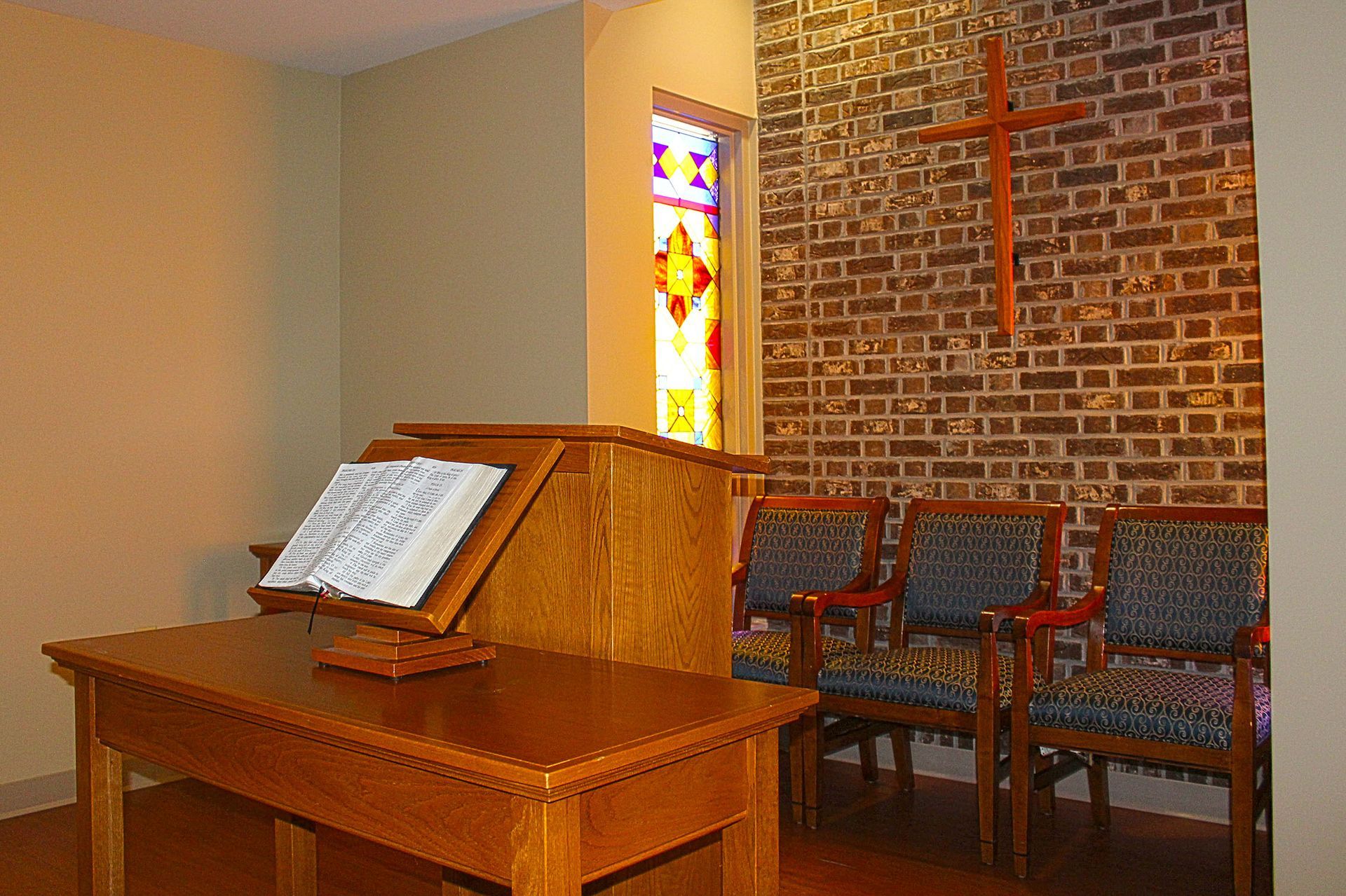 A wooden table with a bible on it in front of a brick wall