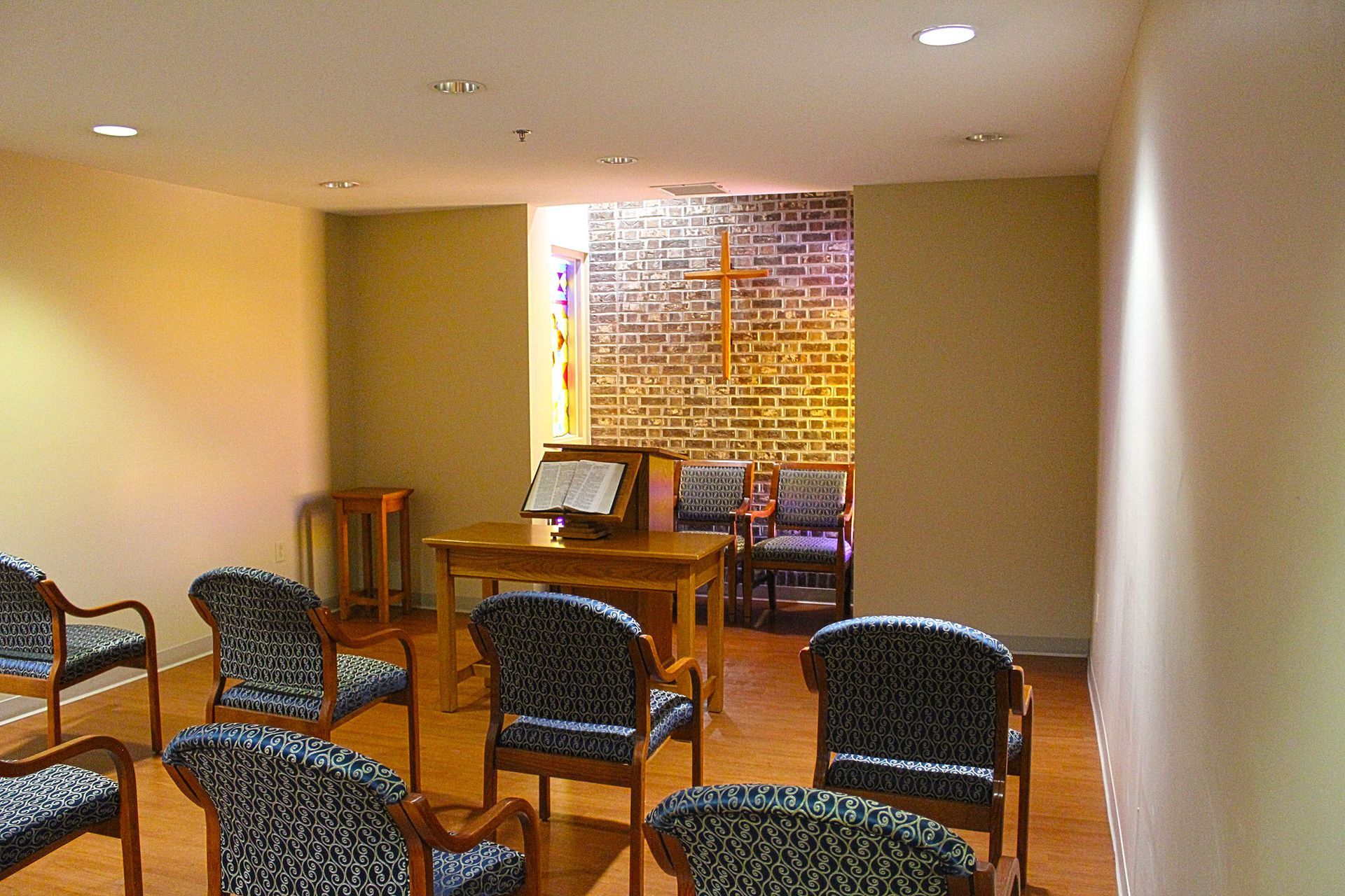 A room with chairs and a table with a cross on the wall