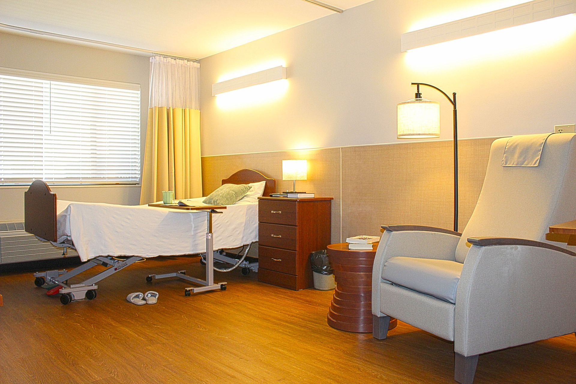 A hospital room with a chair and a bed