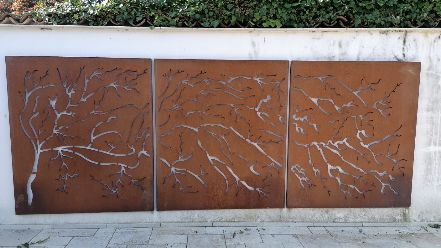 Tre pezzi di metallo arrugginito sono appoggiati su un muro bianco.