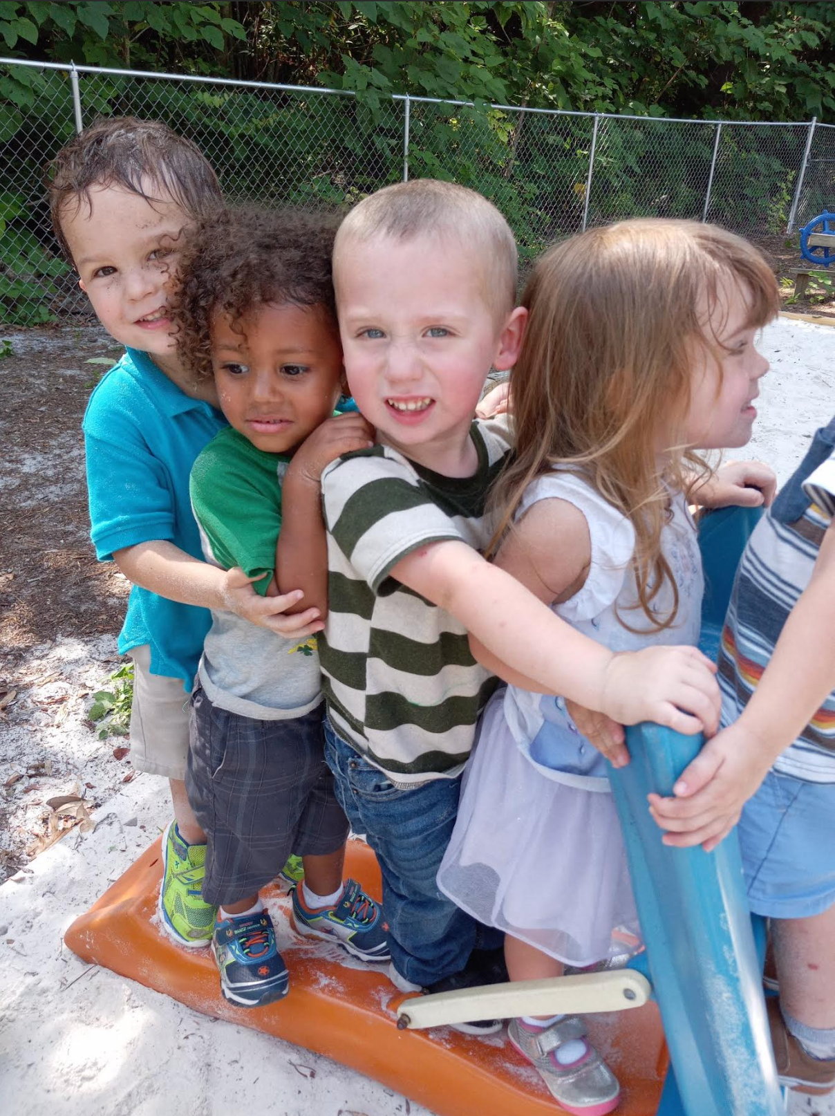 A group of children are posing for a picture on a slide.