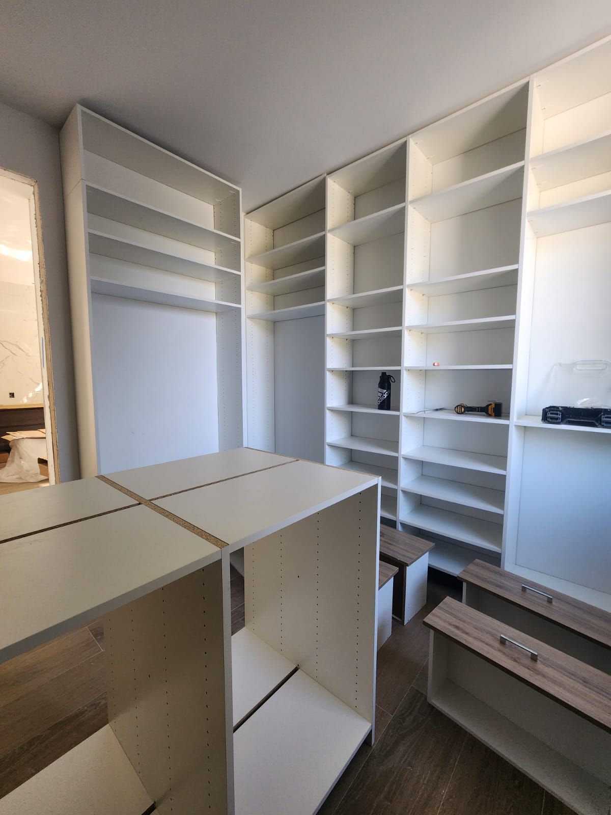 A walk in closet with lots of shelves and a bench.