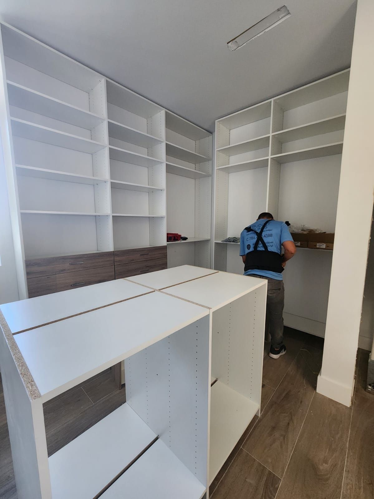 A man is working on a walk in closet.