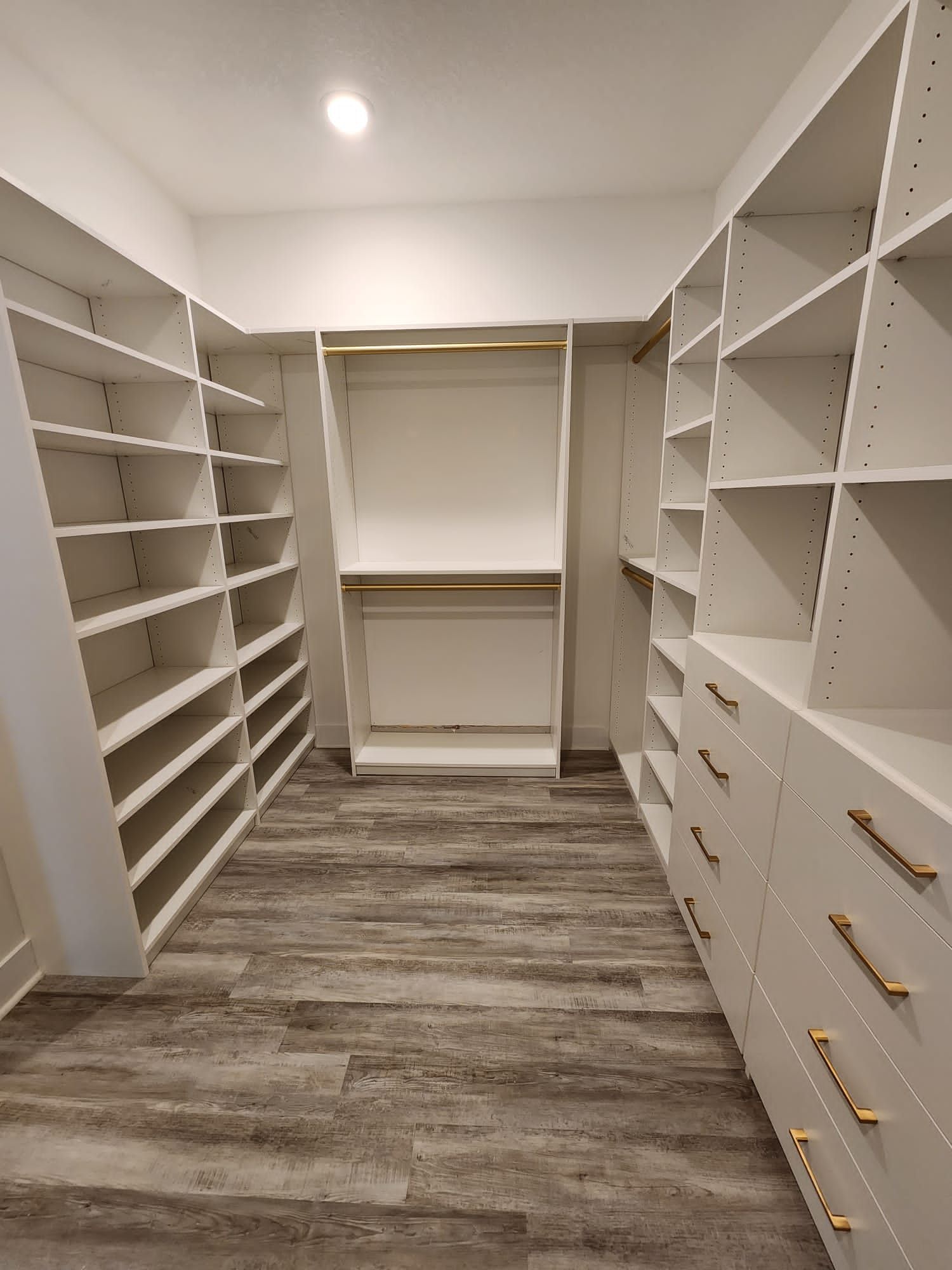 A walk in closet with lots of shelves and drawers.