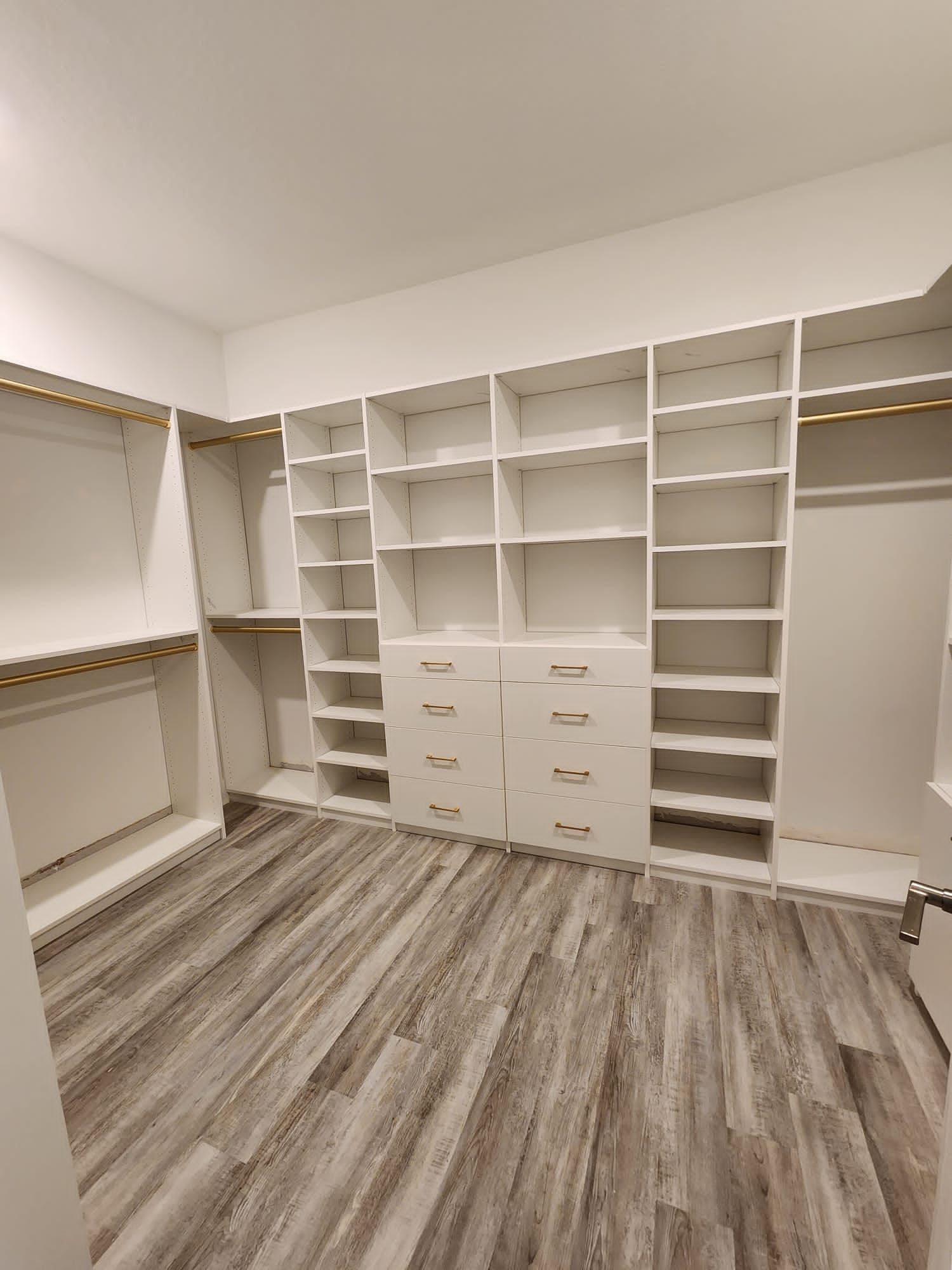 A walk in closet with lots of shelves and drawers.