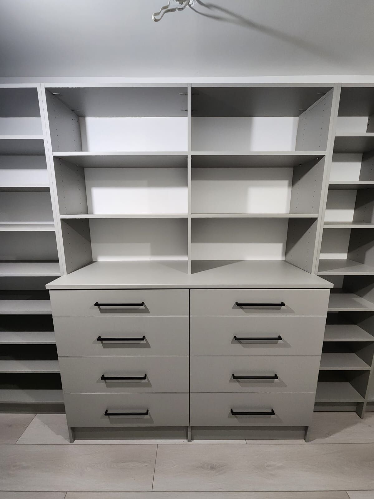 A walk in closet with lots of shelves and a light on the ceiling.