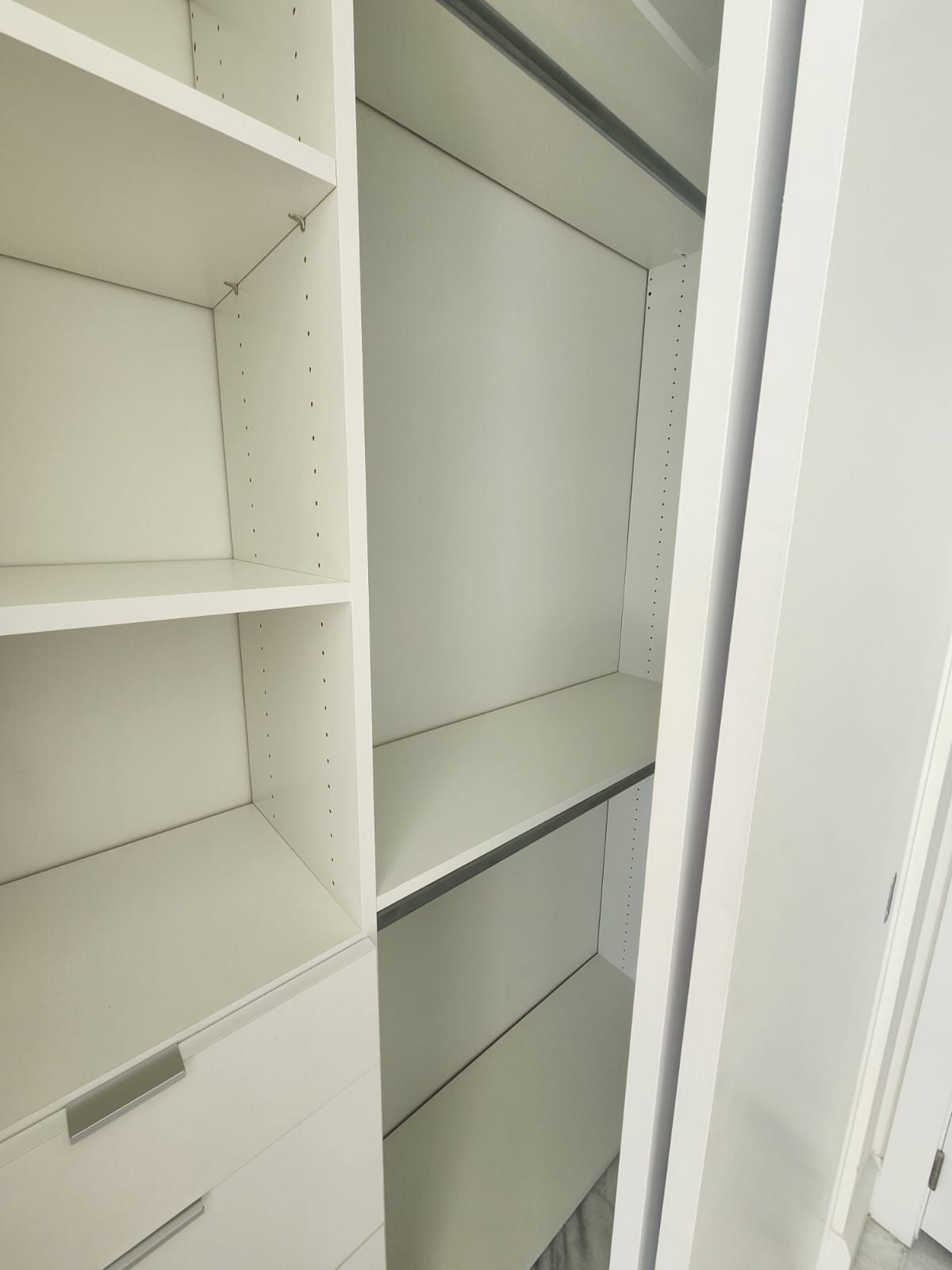 A  sliding reach in closet with a lot of shelves and drawers