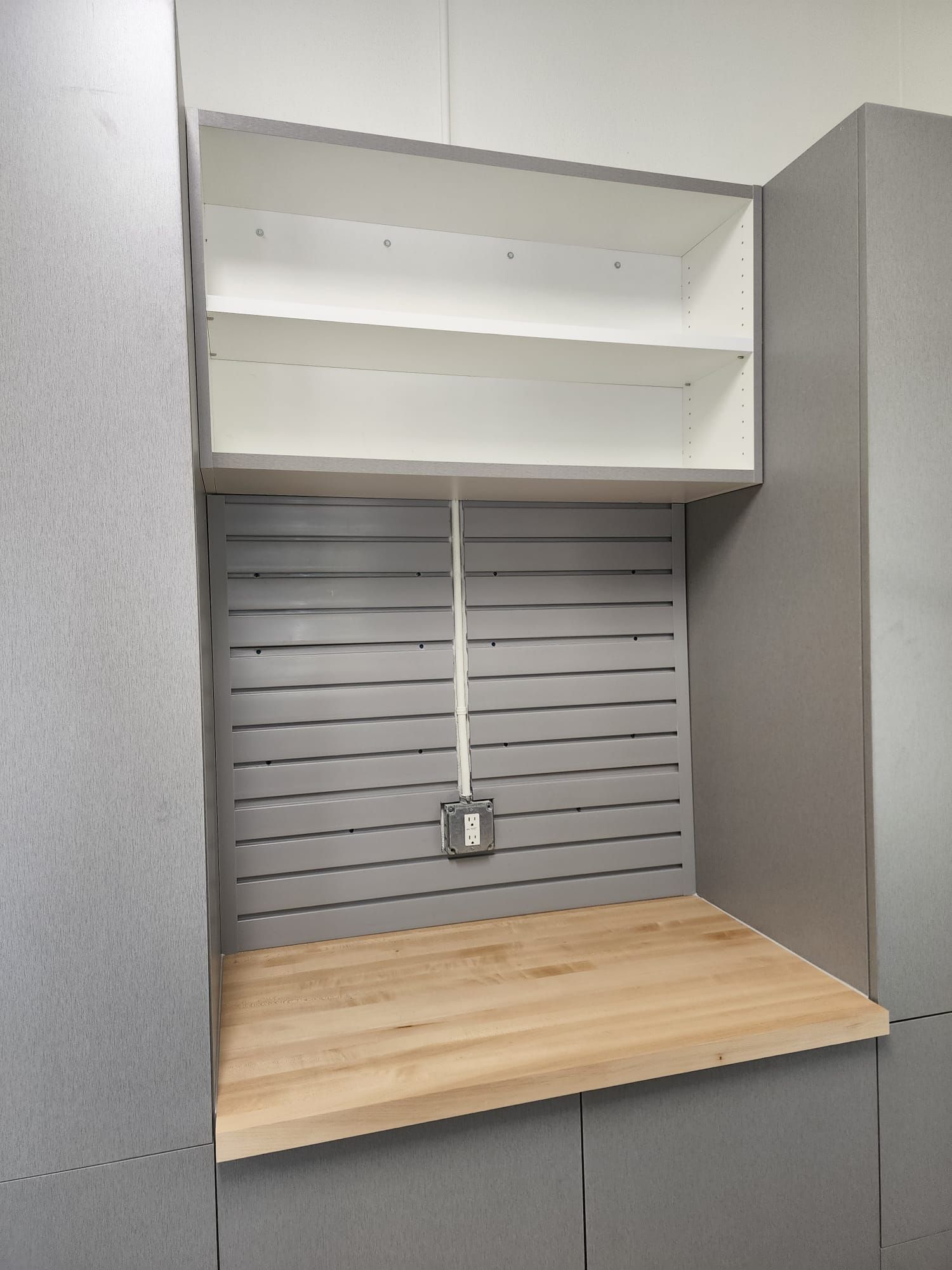 A  custom garage cabinet  with a wooden counter top and shelves.