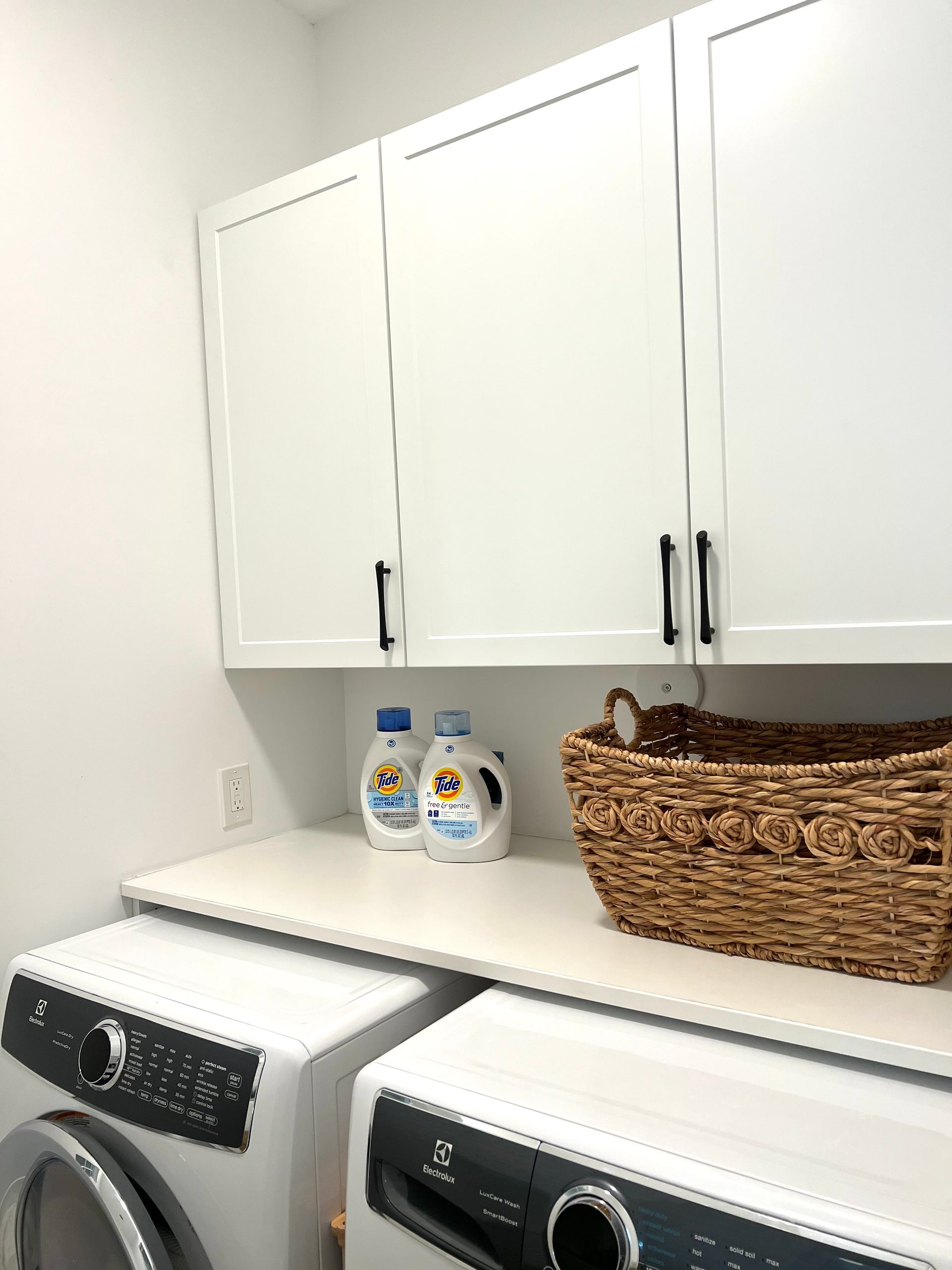 A laundry room with a washer and dryer and a basket on the counter.