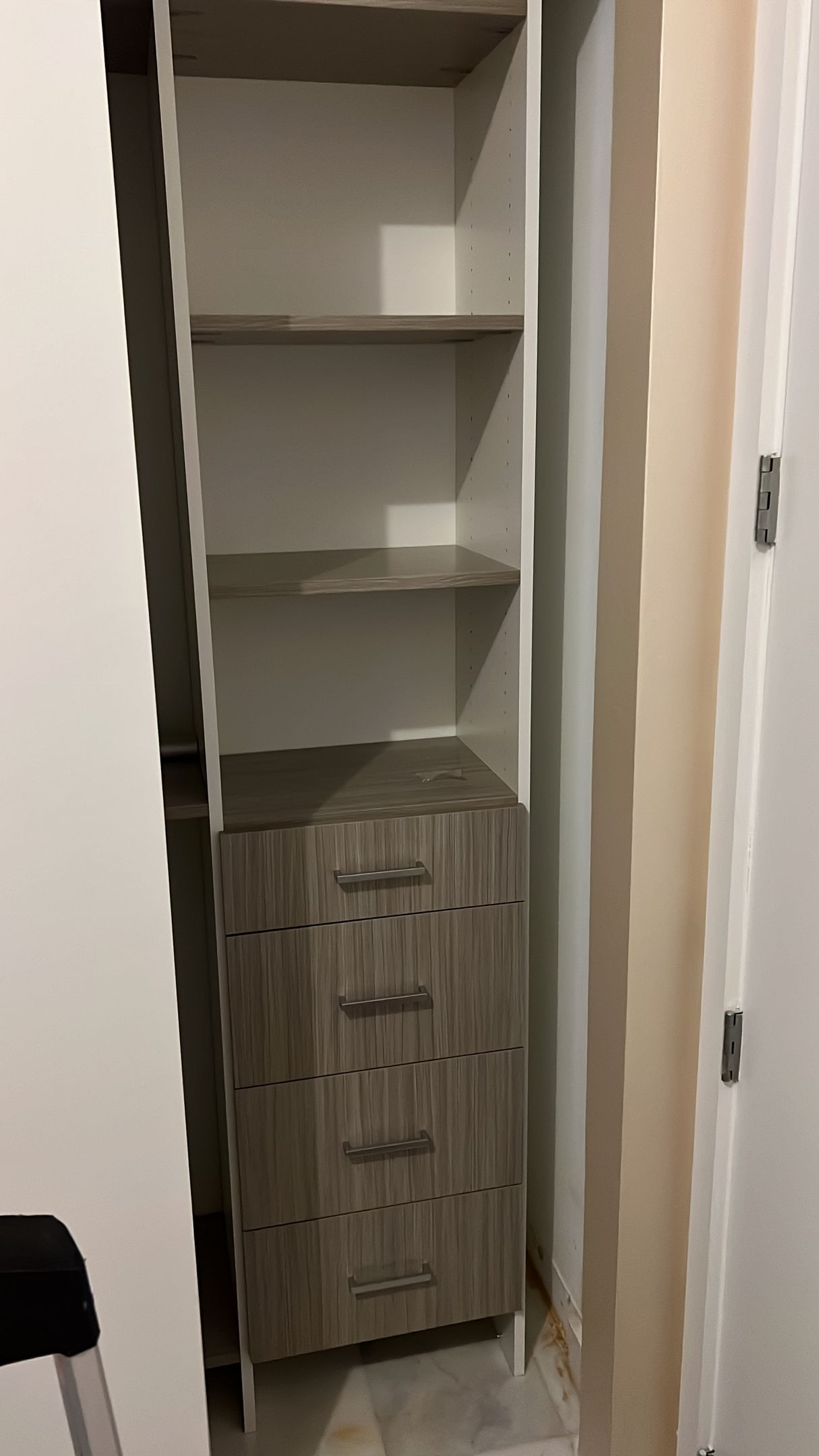 A closet with shelves and drawers is being built in a room.