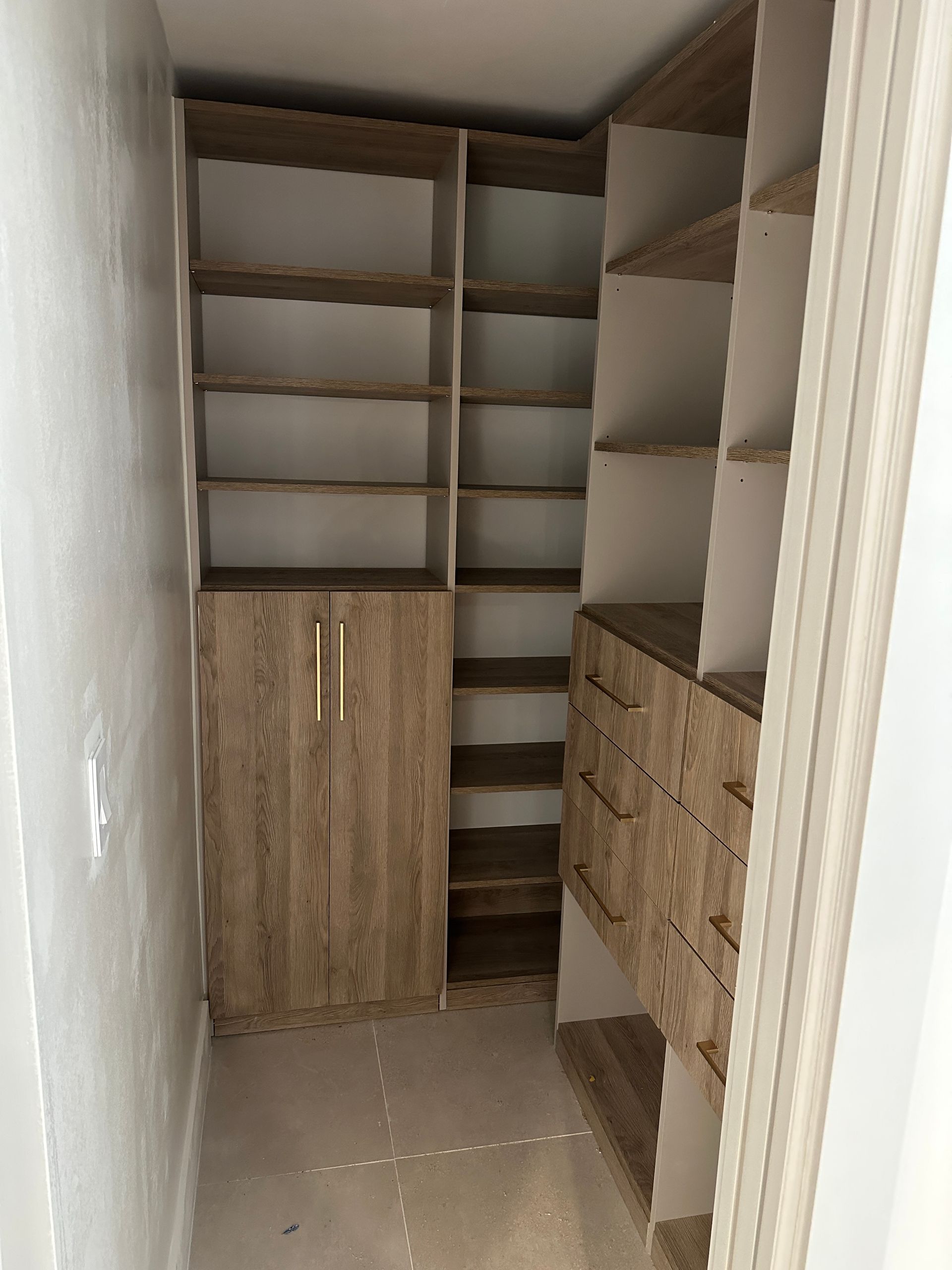 A kitchen pantry with lots of shelves and drawers.