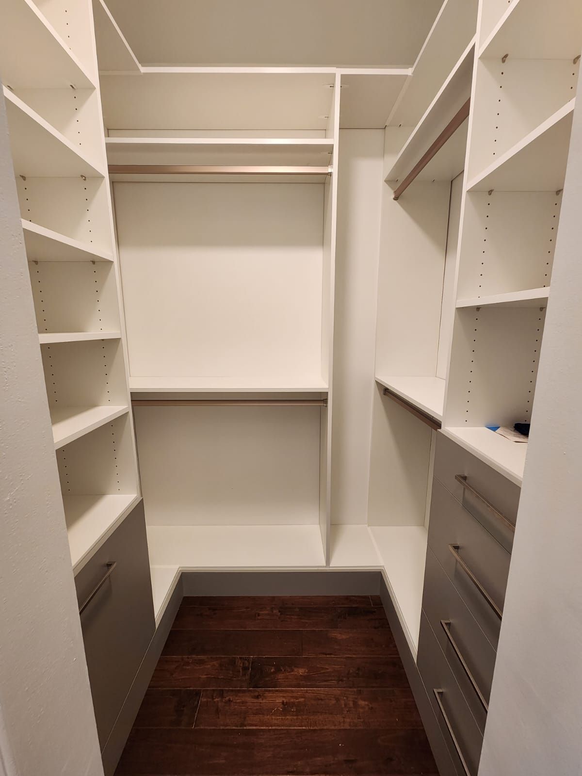 A walk in closet with lots of shelves and drawers.