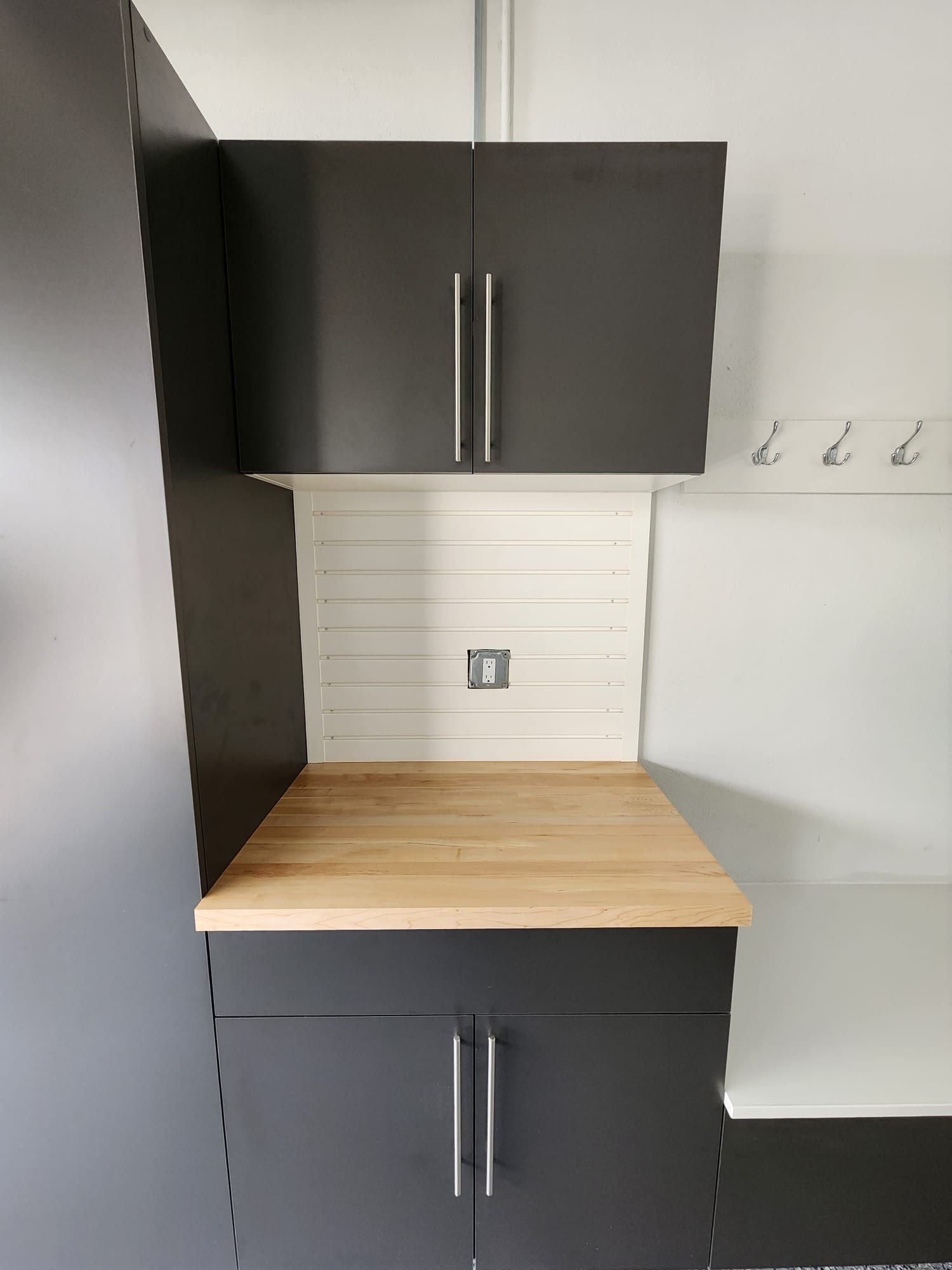 A garage with black cabinets and a wooden counter top.