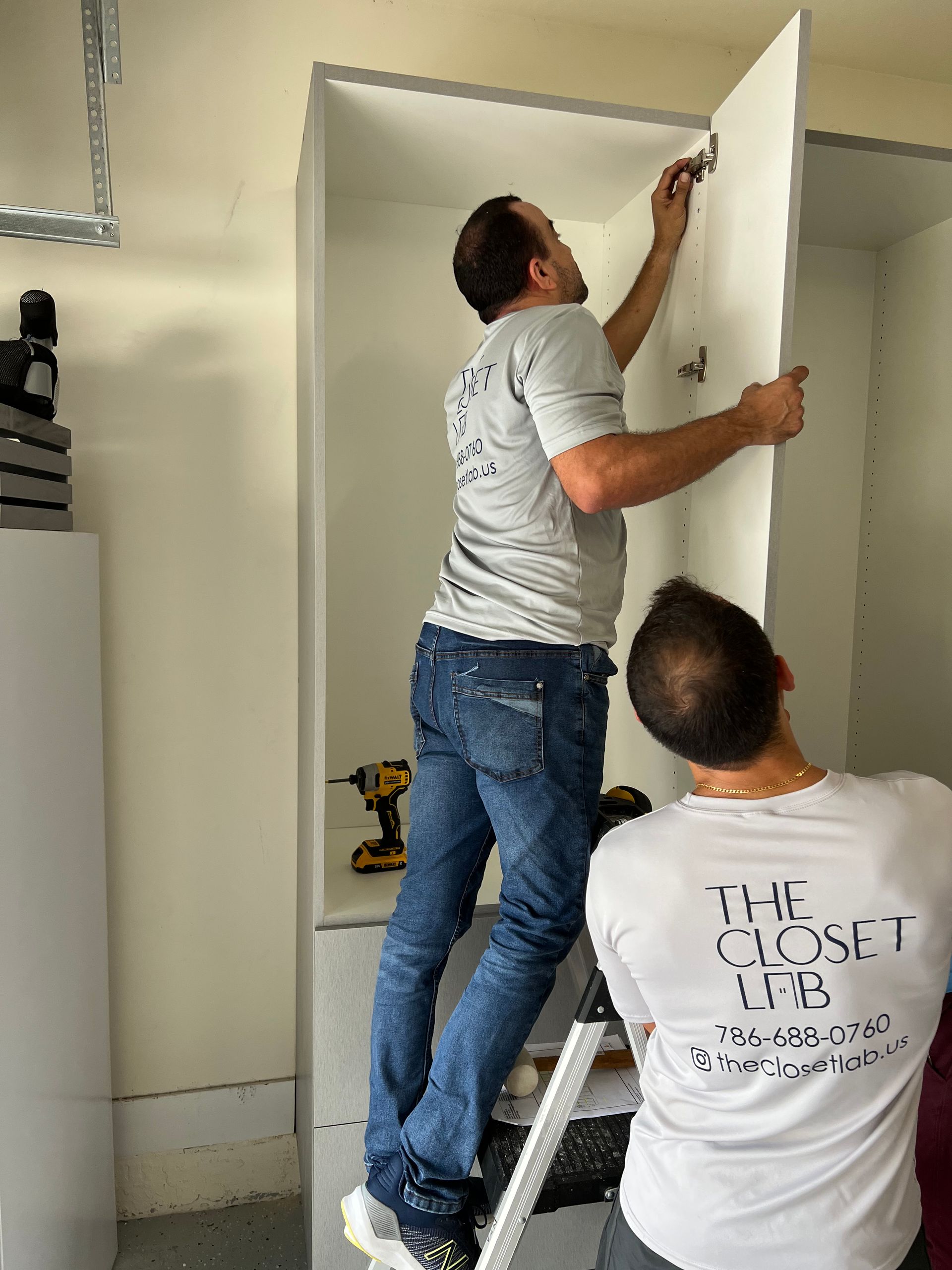 Two men are working on a cabinet in a garage.