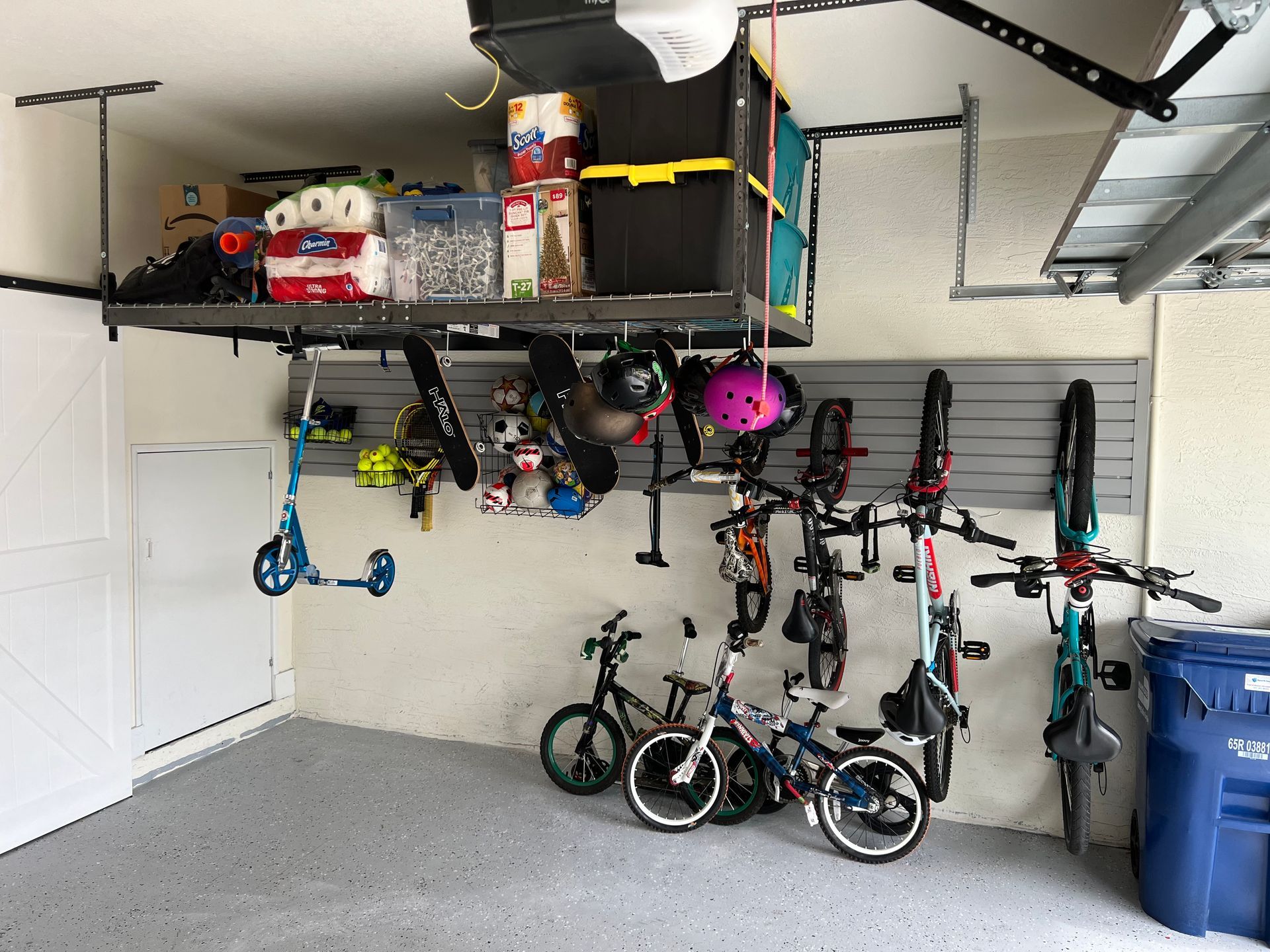 A garage with bikes and scooters hanging from the ceiling