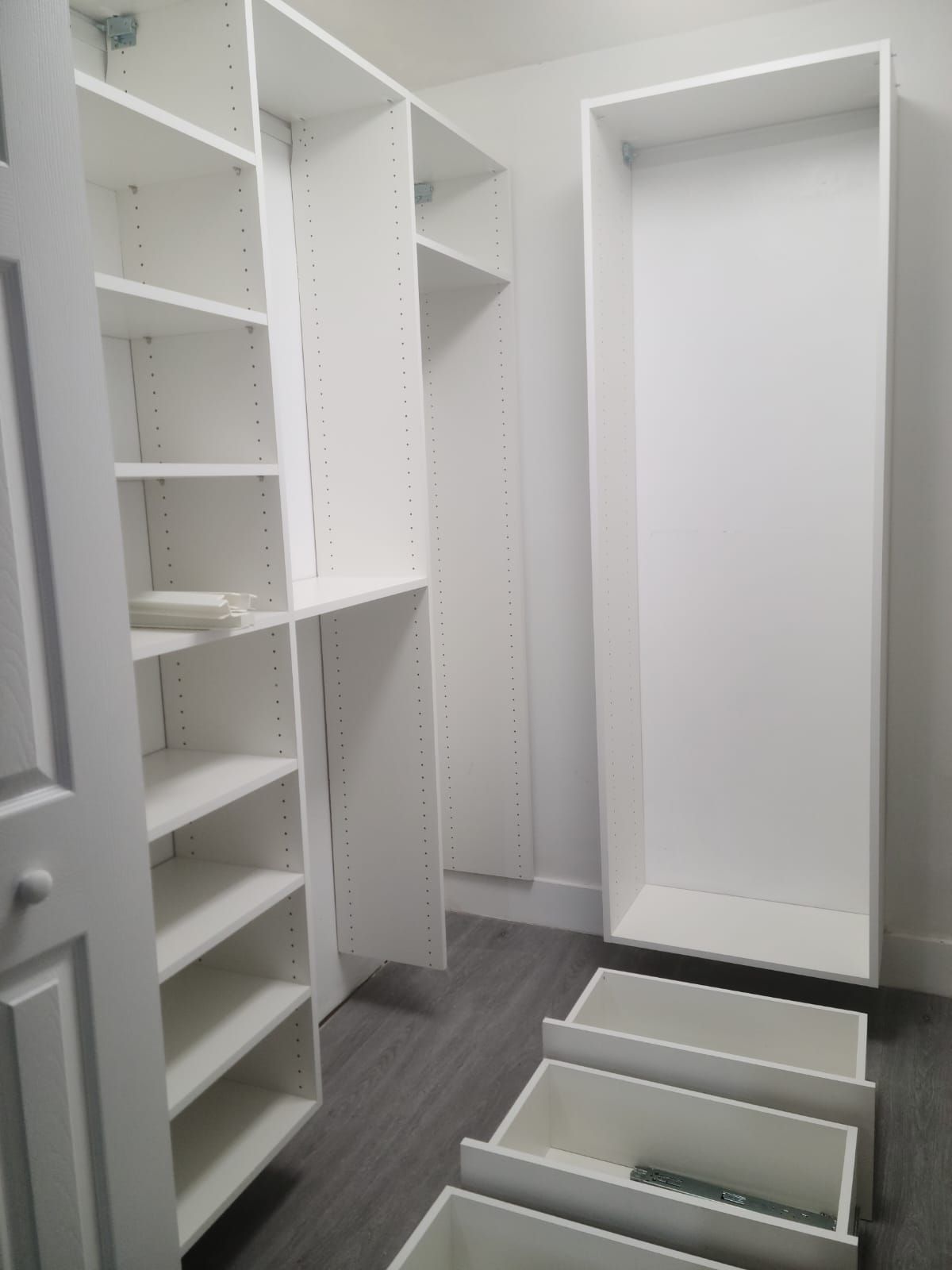 A custom white walk in closet with lots of shelves and drawers