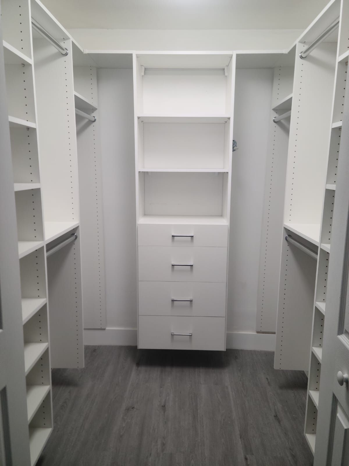 A white  walk in closet with lots of shelves and drawers.