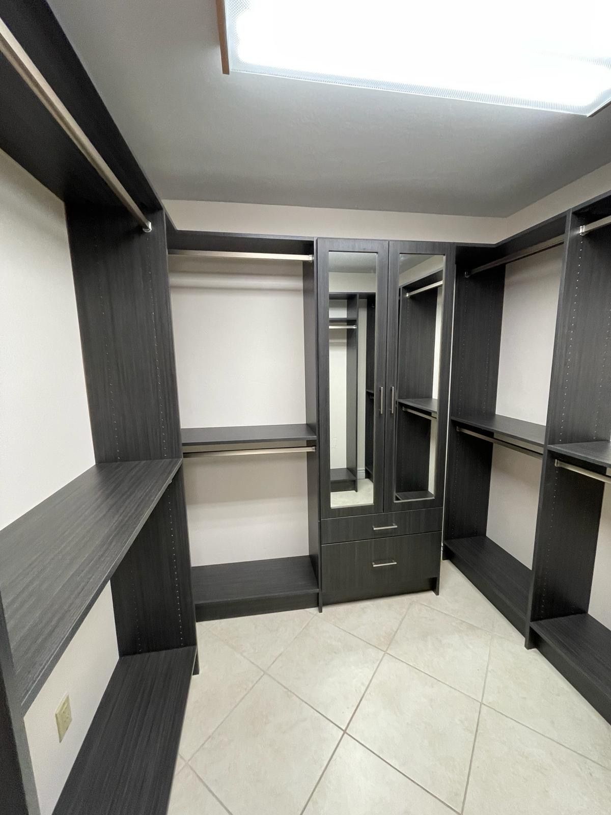 A walk in closet with wooden shelves and a white wall.
