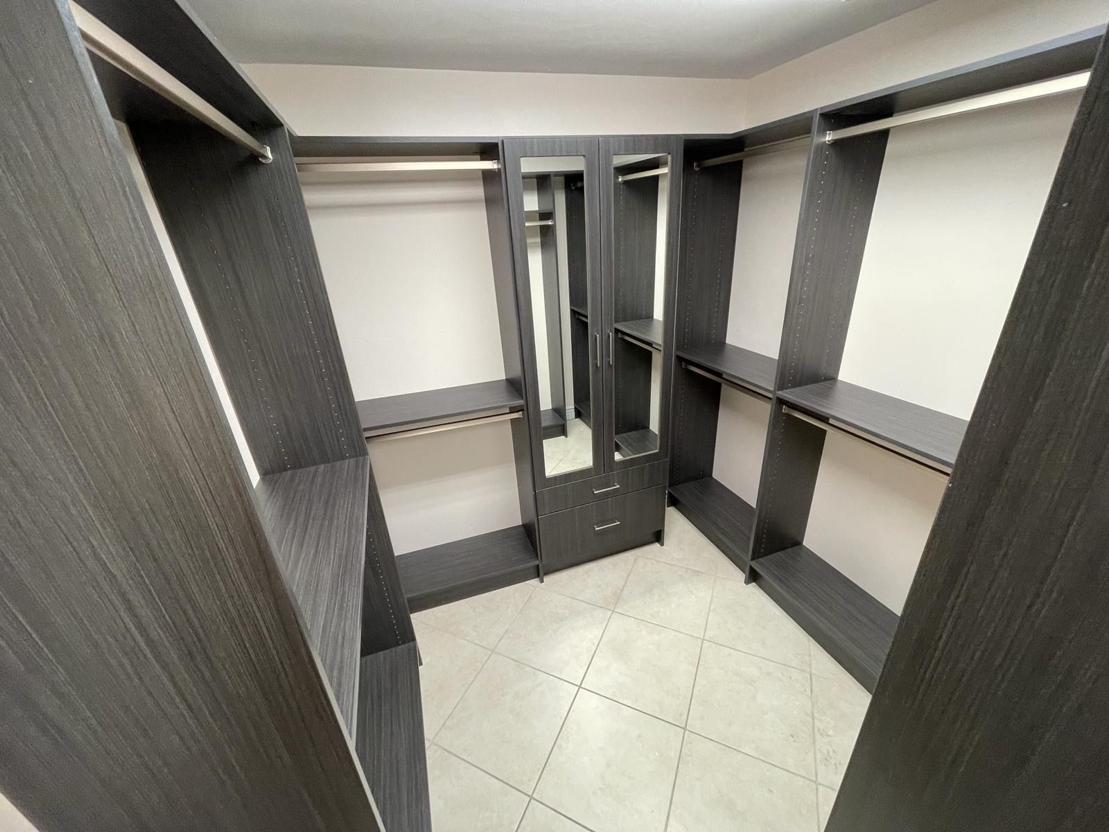 A walk in closet with a lot of shelves and a mirror.