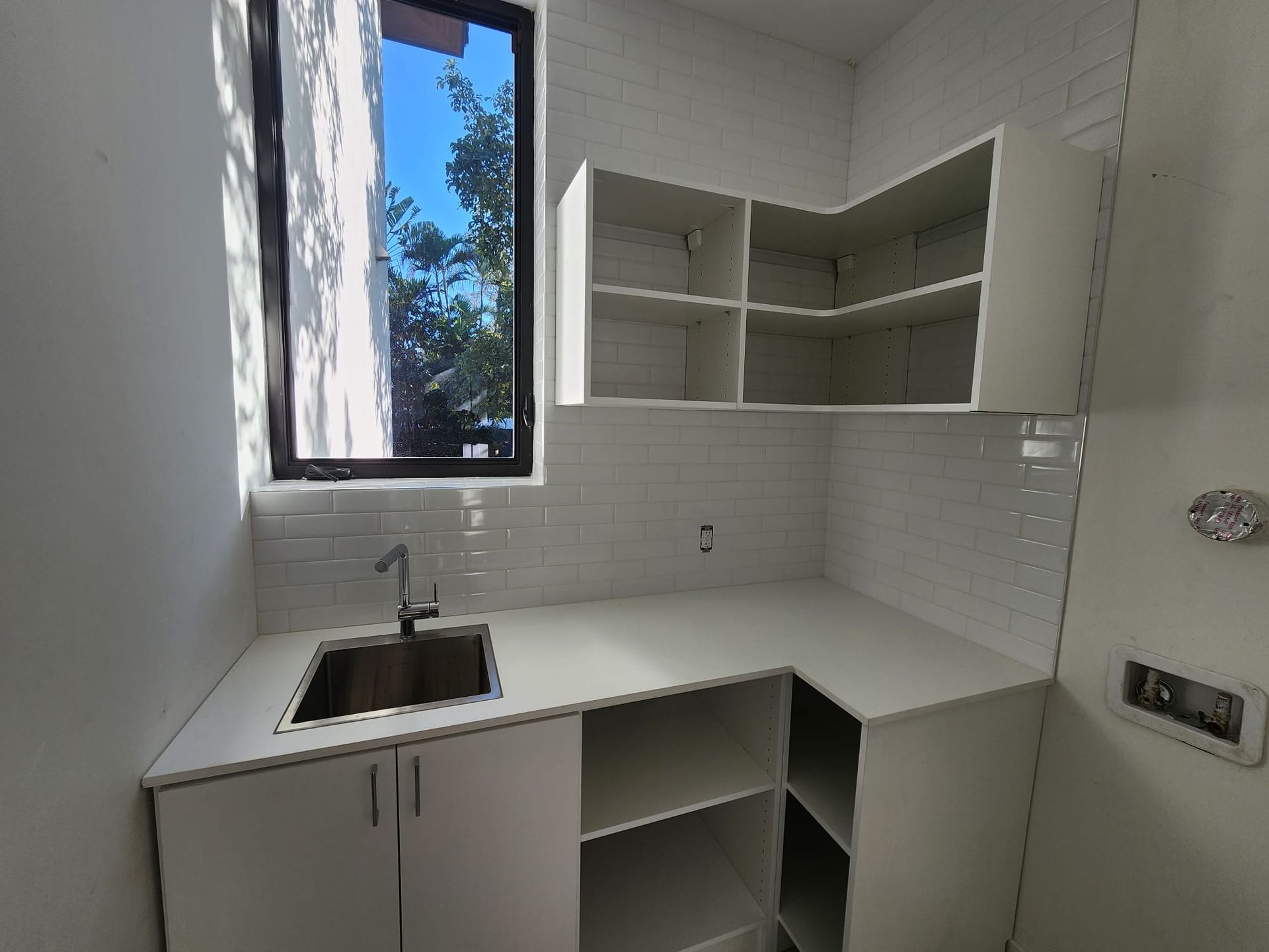 A kitchen with a sink and shelves and a window