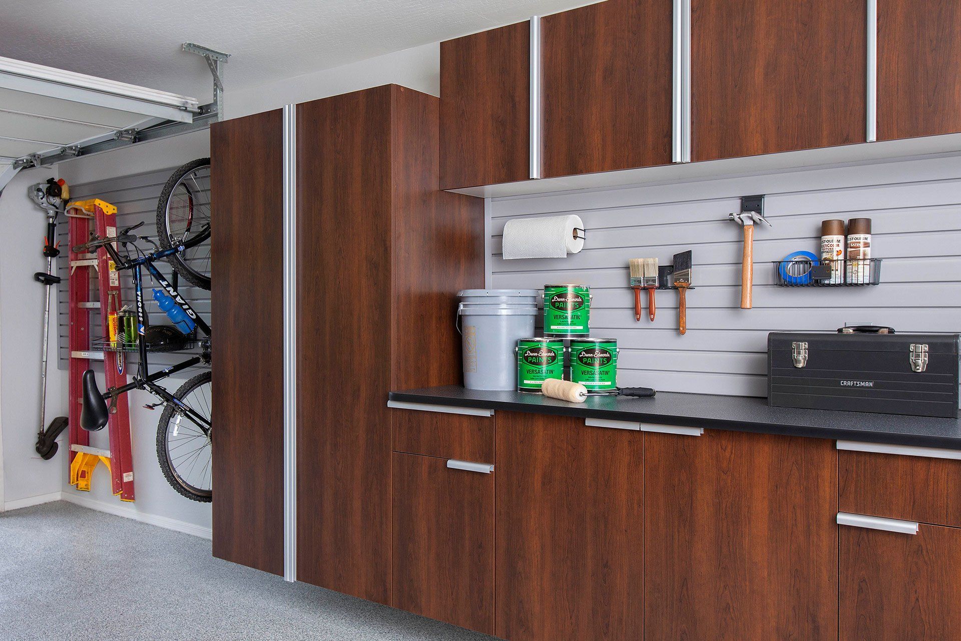 a garage with wooden cabinets and a slatwall storage accessories .