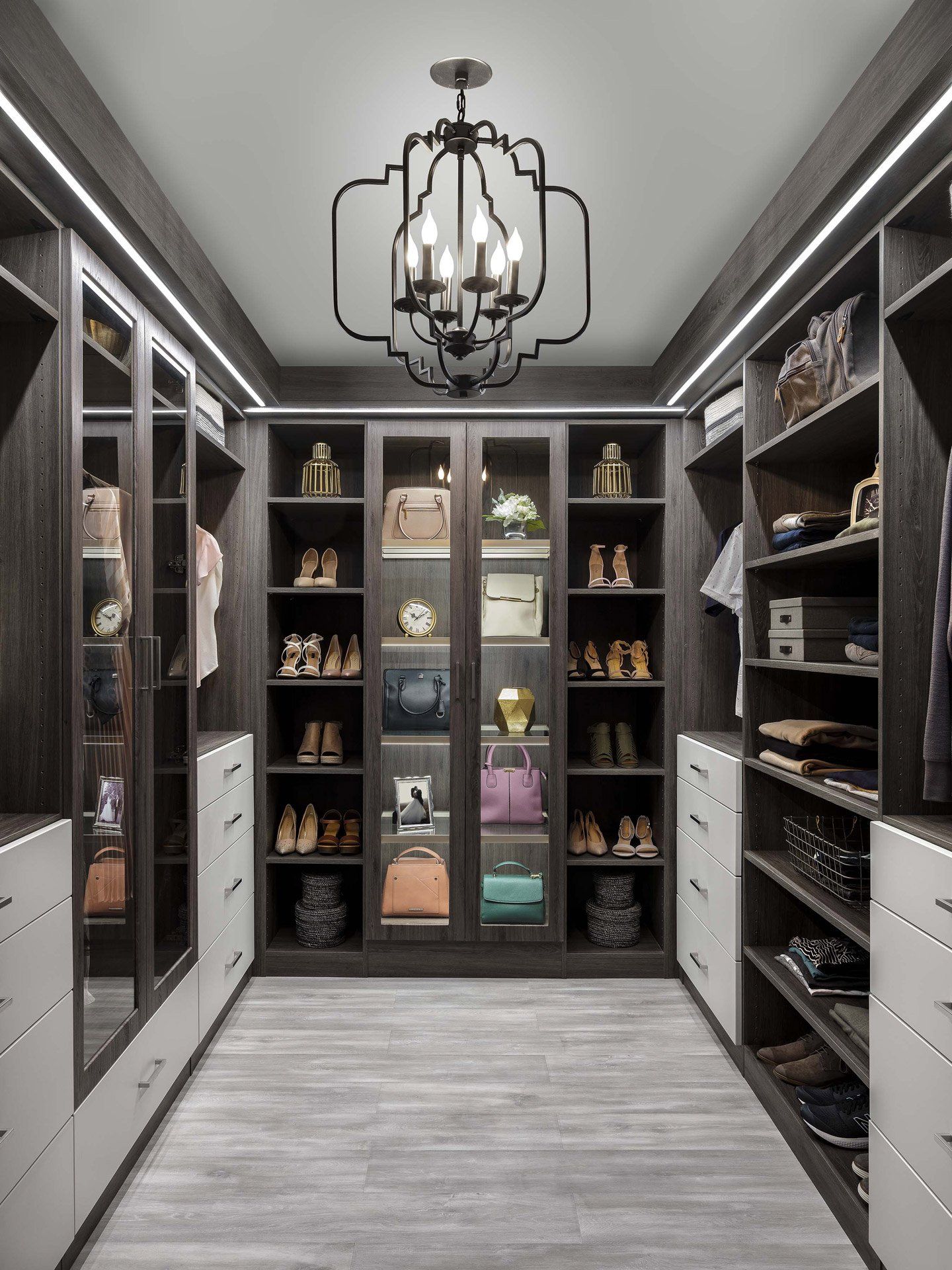 a walk in closet with lots of shelves and a chandelier .